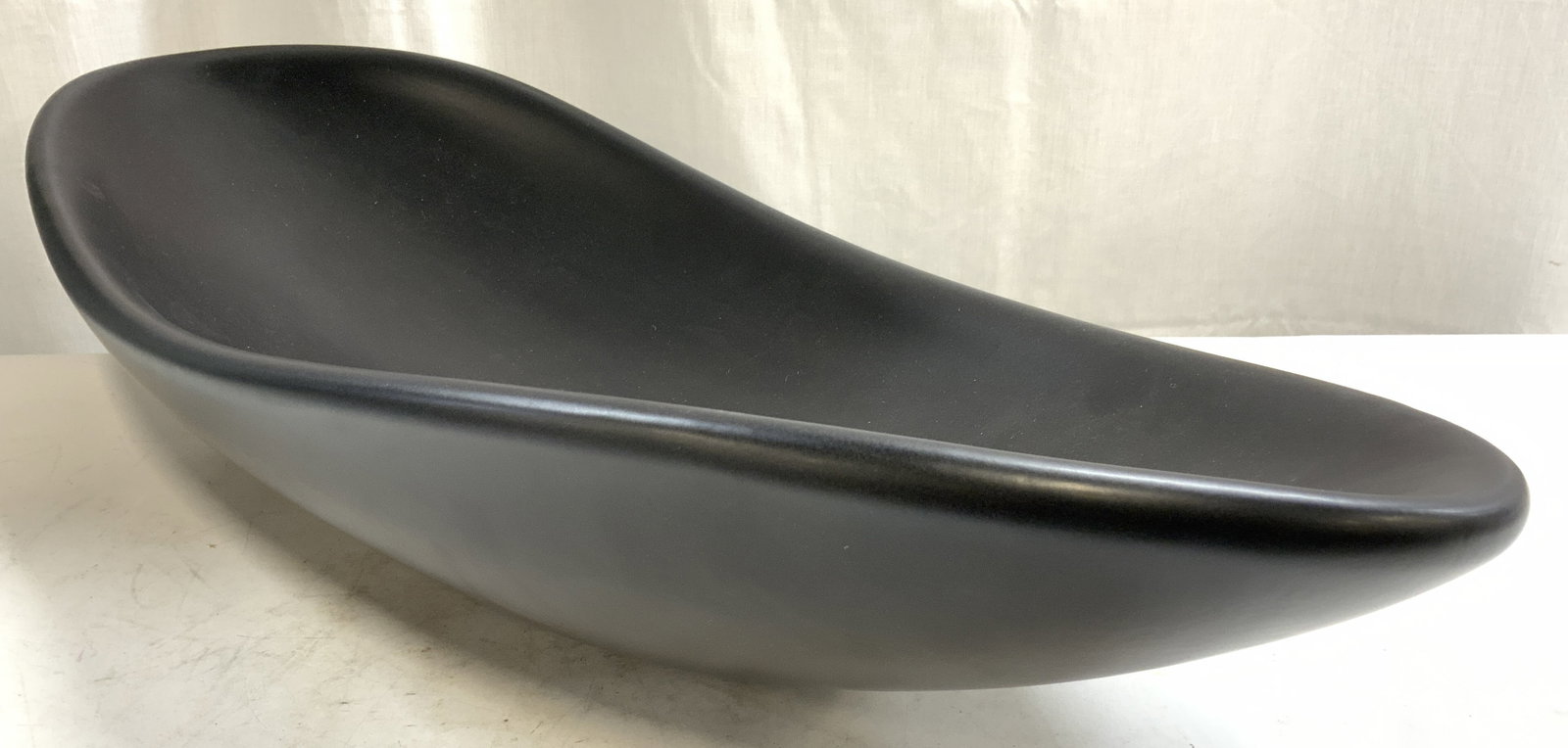 Global Views Oblong Platter Bowl Matte Black: Tag on Underside reads GLOBAL VIEWS. Centerpiece bowl is matte black toned & has oblong form. Vessel appears to be porcelain. Piece measures approximately 30 inches ling 12.5 inches wide 6 inches tall