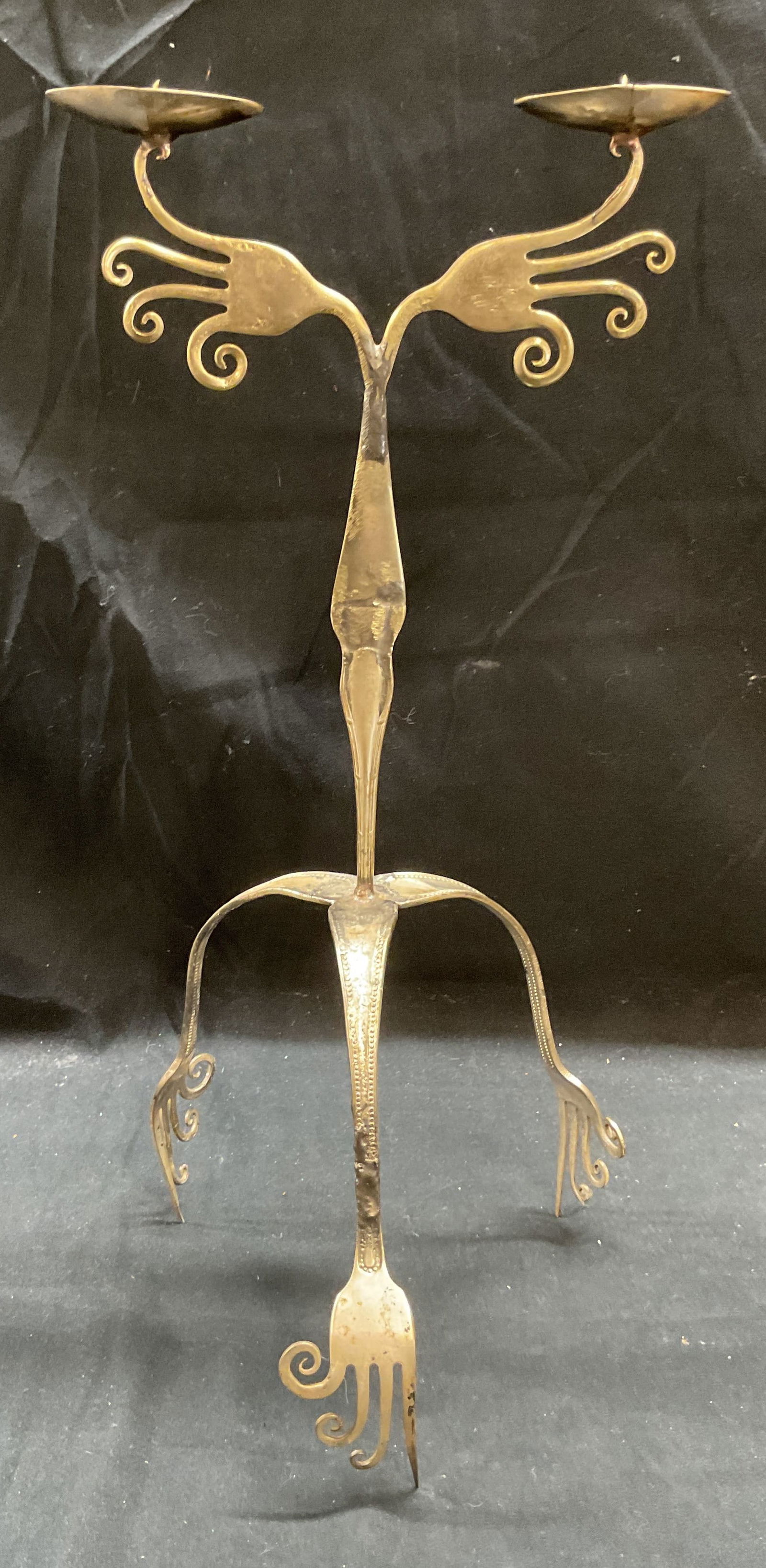 SGND Handcrafted Silver Tn Fork Candle Holder 1996: Vintage signed handcrafted cutlery fork two arm candle holder. Silver tone metal. Tripod footed base with swirled design. Signed on base, illegible. Dated 1996. Measures approx 7 x 15 inches. Some wea