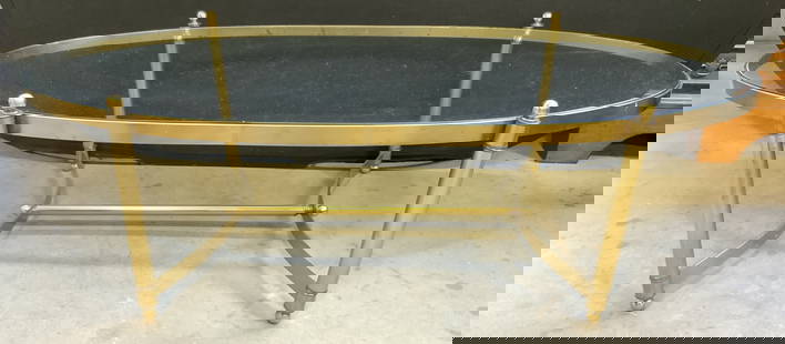 Vintage Glass Top Brass Coffee Table: Coffee table is vintage. Piece has gold toned brass base with 4 feet. Table includes oval form glass insert top. Table legs have stretchers in between. Measures approximately 53 inches long 24 inches