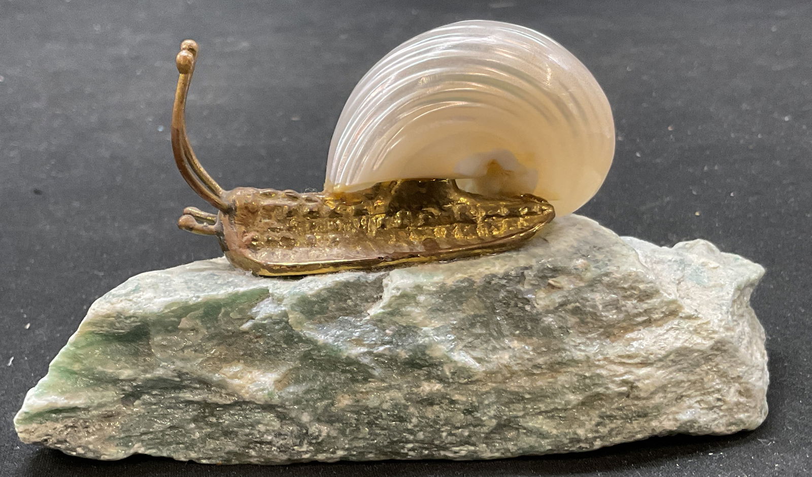 Vtg Mother of Pearl Brass Jadeite Snail Sculpture: Vintage mother of pearl brass stone snail sculpture. Brass or bronze plated snail body with mother of pearl shell snail on top of jadeite rock. 5.25 x 2 x 2.5 inches. Some surface wear consistent with