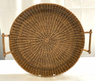 Woven Wicker Rattan Serving Tray W Handles: Serving tray is woven wicker/rattan. Piece is tan toned. Serving tray has circular form. Sides of tray have handles. Edges of serving tray are raised. Piece measures approximately 18 inches wide 16 in