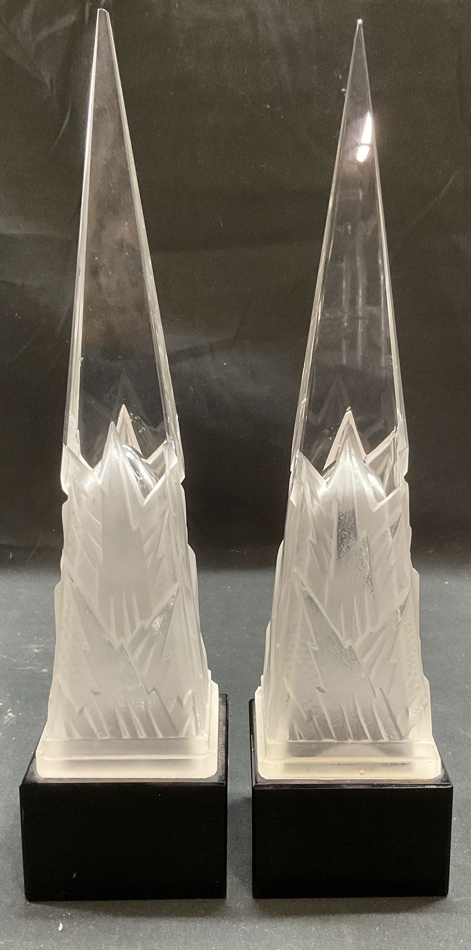 Pair Frosted Cut Crystal Icicle Obelisks: Pair of cut crystal obelisks. Frosted and clear crystal with black base. Icicle motif. Style of Barolac. No visible signatures or marks. Pieces have weight. Measure approx 3 x 3 x 12.25 inches. Wear t