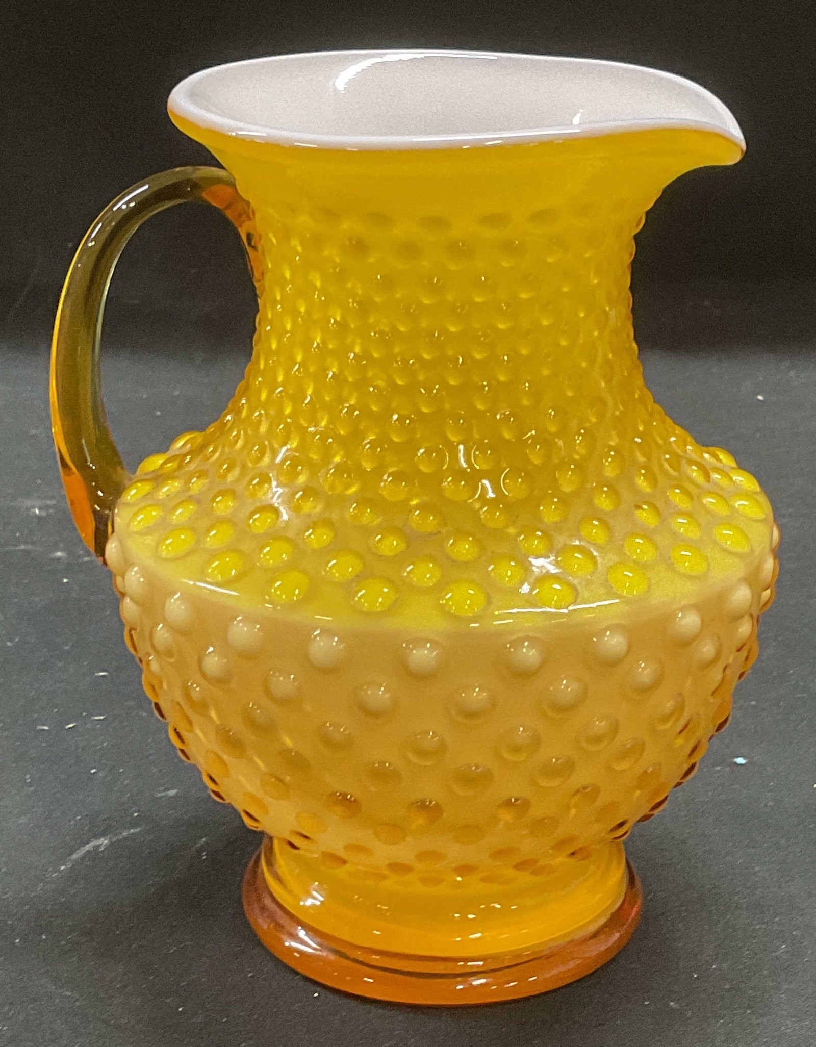 Vintage Yellow Art Glass Hobnail Pitcher: Vintage art glass pitcher with hobnail pattern in yellow and white. Measures approx 4.5 x 5.75 inches. Some wear including scratching. Art glass pitcher, hobnail pitcher, yellow pitcher, tableware, ta