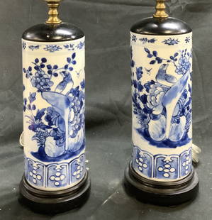 Pair Vintage Asian Porcelain Table Lamps: Lot includes 2 table lamps. Each are white toned and porcelain with floral, leaf & butterfly detail. Lamps each have black toned circular form bases . Lamps include harps and finial. Each lamp appears