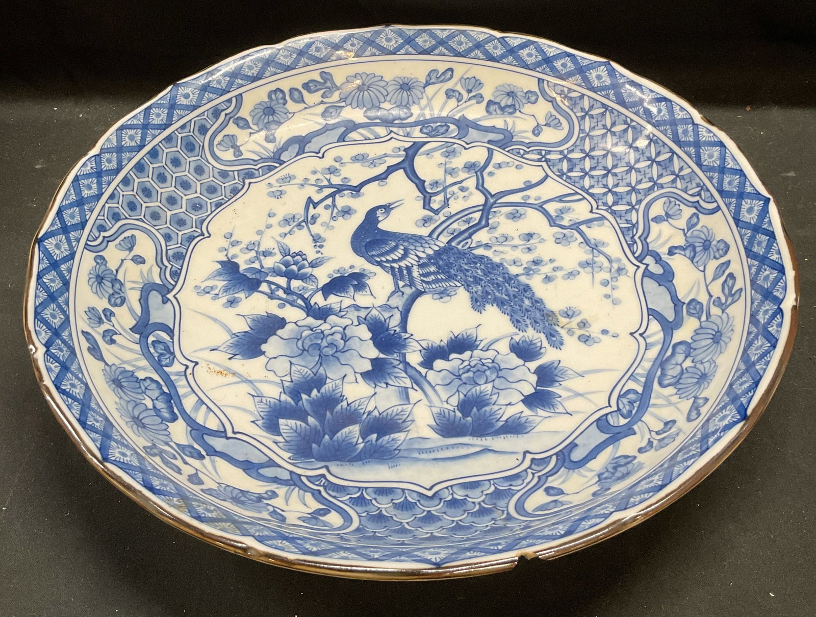 House of Global Art Peacock Porcelain Bowl Japan: Blue and white hand painted porcelain bowl by House of Global Art. Peacock and floral motif. Signed with Asian characters. Made in Japan. Measures approx 14 x 2.5 inches. Wear including hairline crack
