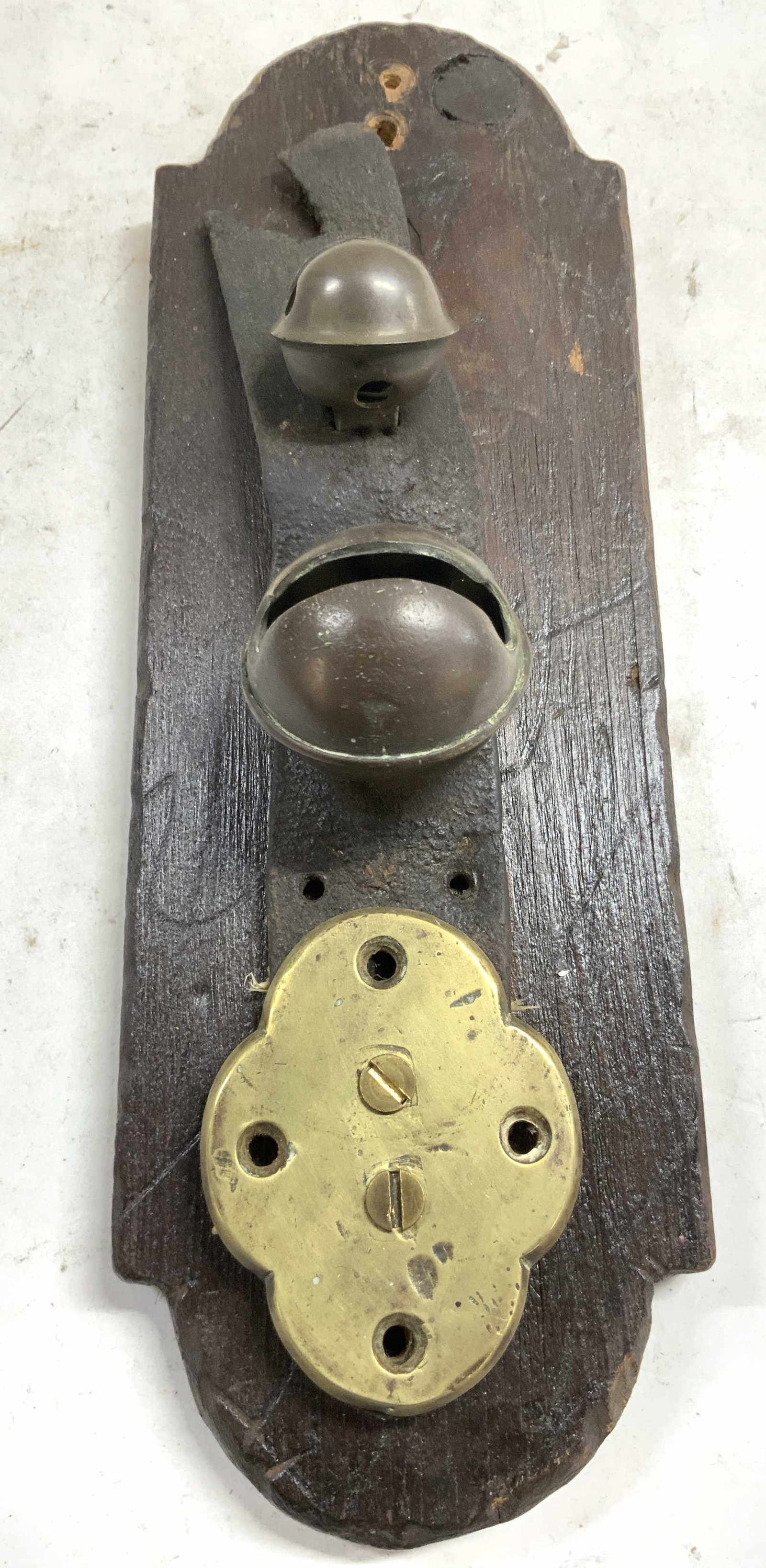 Atq Sleigh Bells On Leather Strap Wood Wall Hnging: Wall hanging appears to be antique possibly vintage. Piece has 2 sleight bells on black toned leather strap with gold toned brass detail. Wall decor is brown toned and wooden. Piece measures approxima