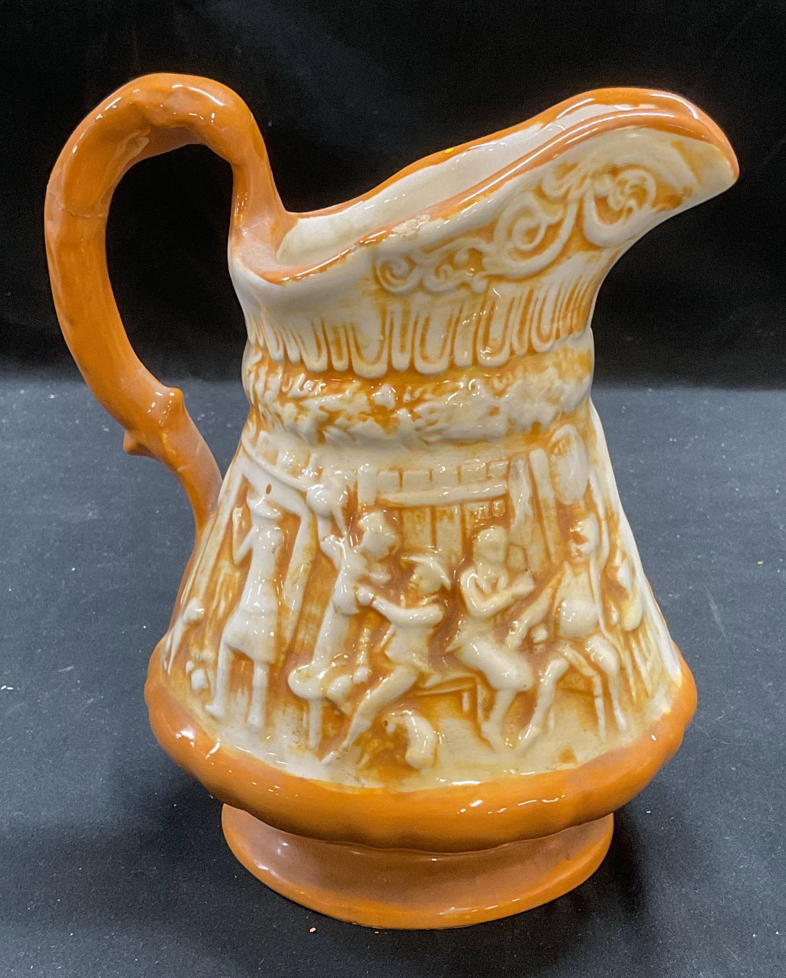 Lobato Orange Ceramic Tavern Scene Pitcher: Vtg Orange ceramic pitcher with raised tavern and equestrian scenes. Signed 1700 Lobato. Measures approx 5.25 x 7. Previously repaired on handle. Lobato pitcher, ceramic pitcher, tavern pitcher, eques