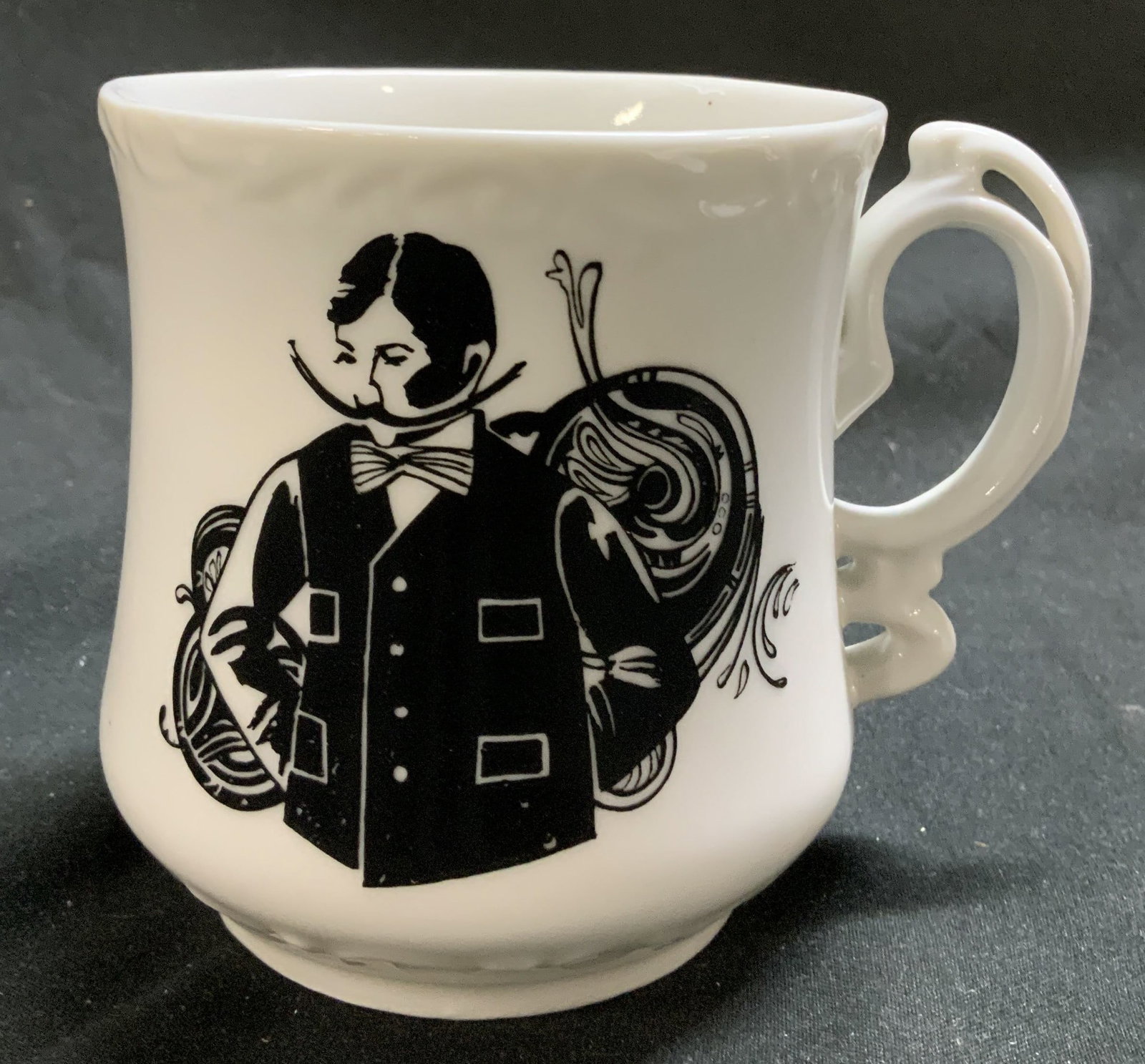 Vntg Gentlemen Illustr Porcelain Mustache Stein: Vntg Gentlemen Illustr Porcelain Mustache Stein Mustache stein featuring an illustration of a gentleman. Mug has a distinctive handle & a mustache guard that sits across the rim. Surface wear consiste