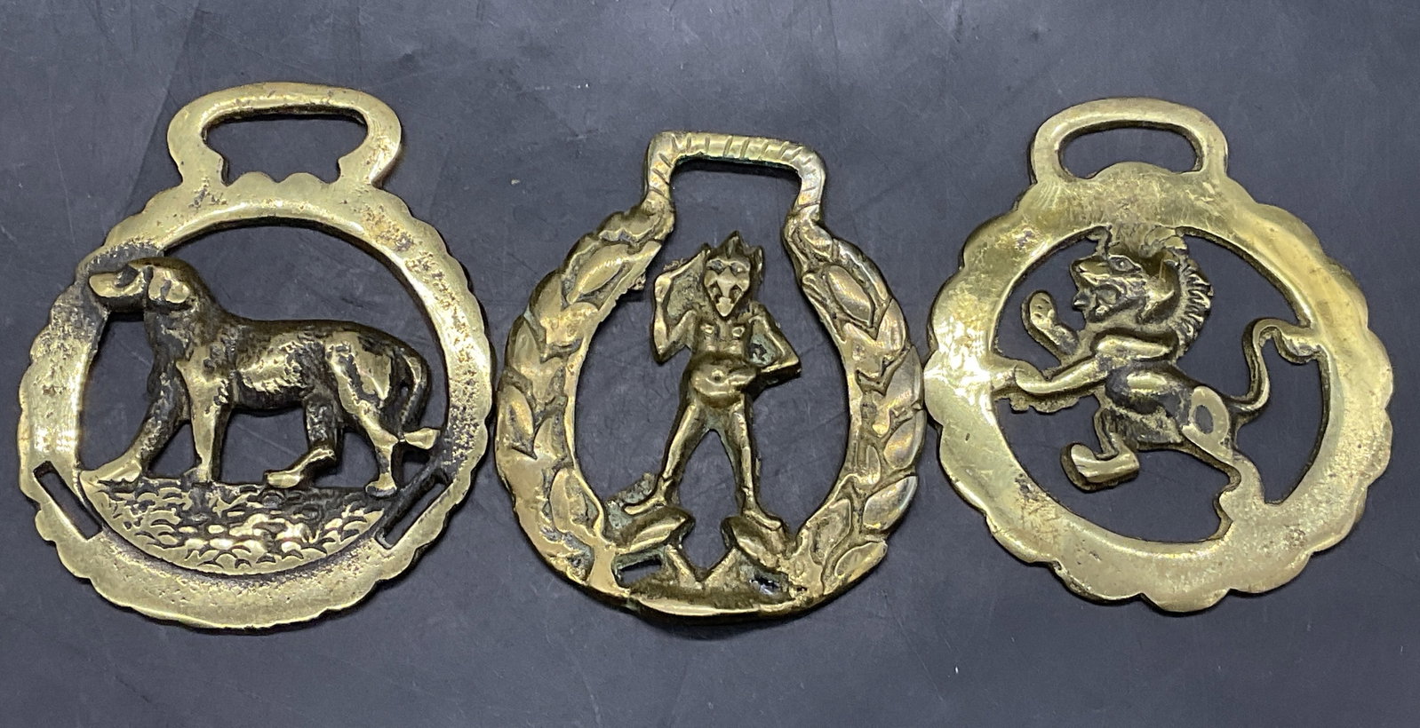 Lot 3 Vintage Horse Brass Medallions, England +: Three Vintage Horse Brass Medallions. Features a dog, a pixie, or a griffin. Dog motif horse brass medallion is marked Made In England on the reverse and measures approx. 4L x 3.25W in. Discoloration,
