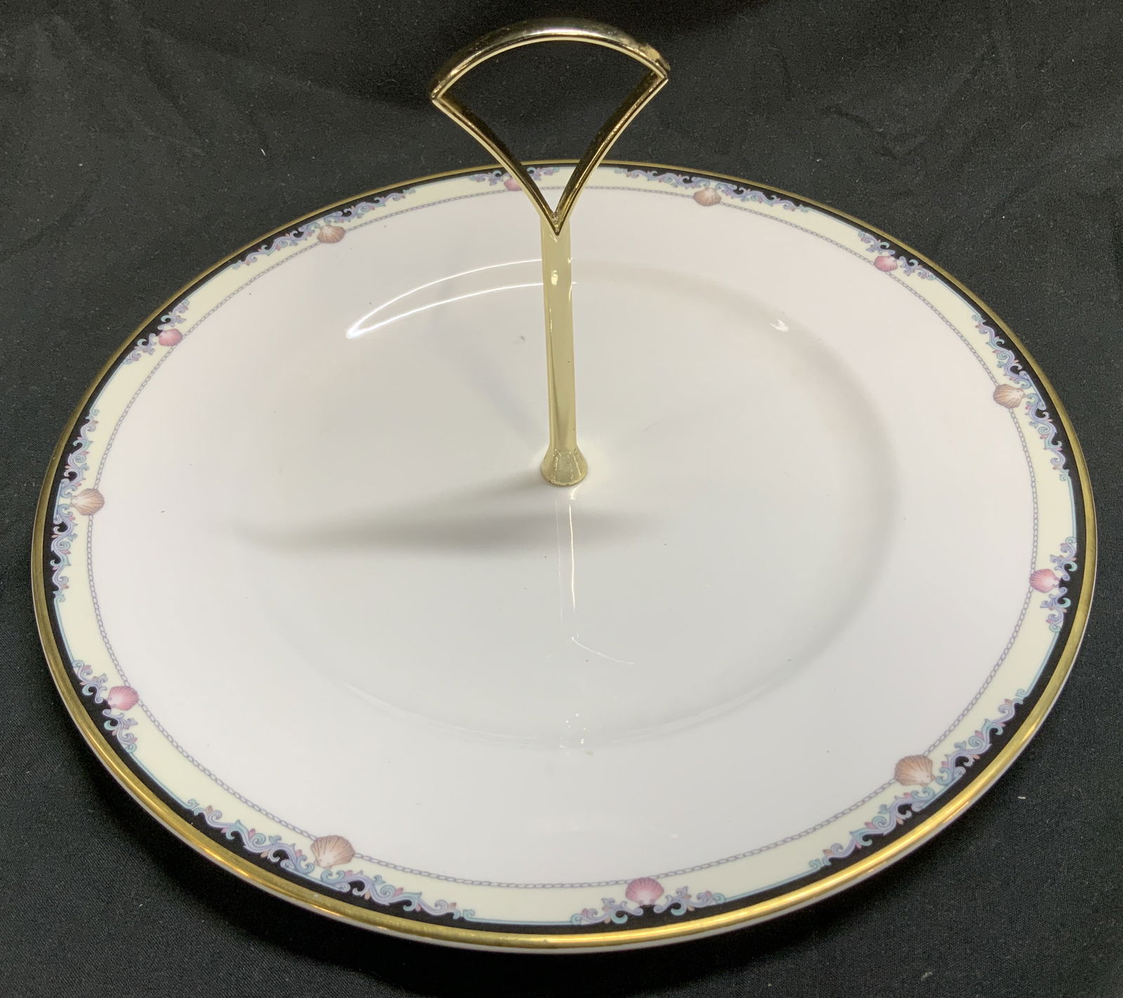1985 Royal Doulton Rhodes Bone China Cake Plate UK: 1985 Royal Doulton Rhodes Bone China Cake Plate Vntg cake plate featuring a Rhodes pattern. Pattern features a distinctive border with shells & scrolls & a gold-colored handle. Cake plate is bone chin