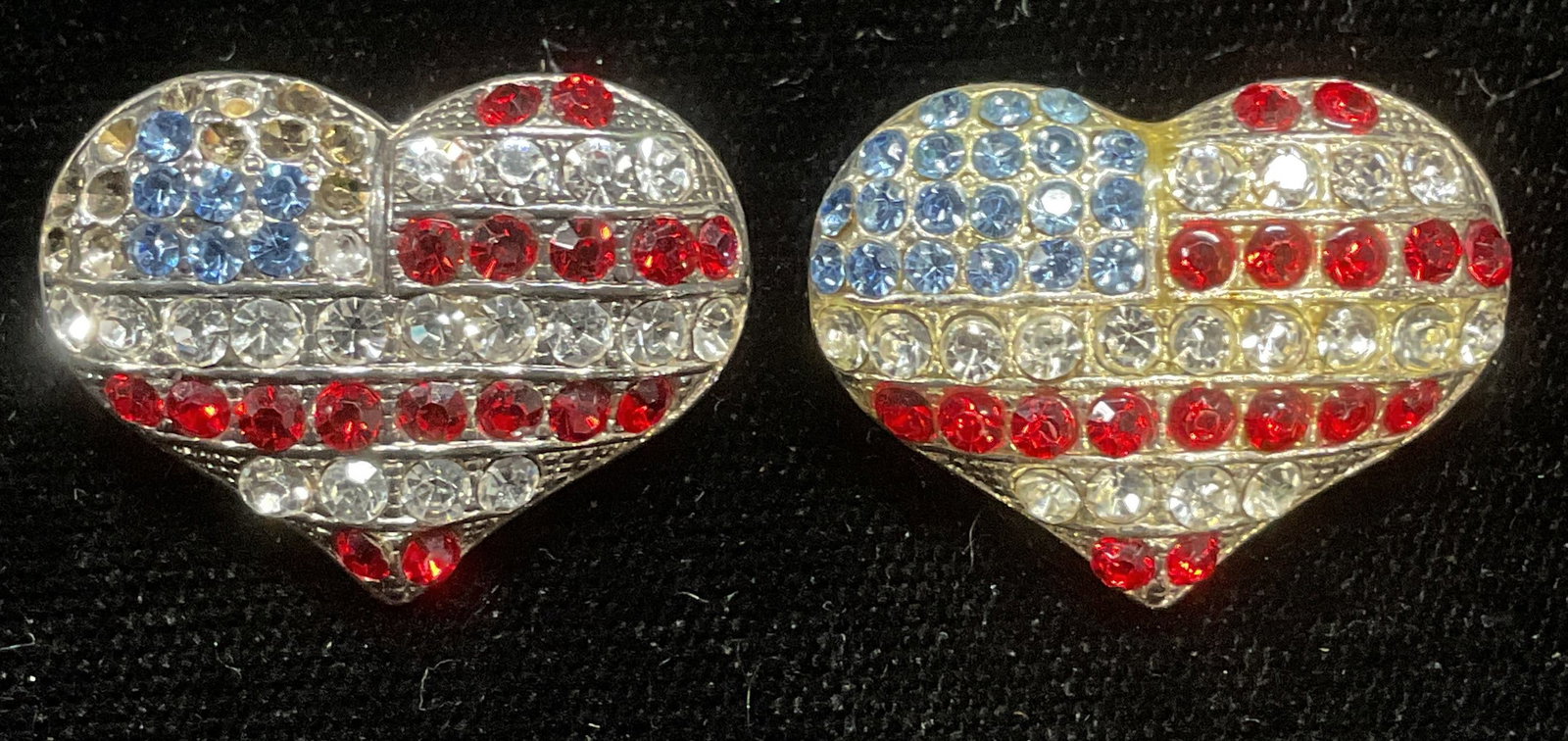 Pair Crystal Heart American Flag Brooches: Pair of matching silver tone red, white and blue crystal heart and American flag motif brooches. Measure approx .75 x 7/8 inches. Some crystals to one piece need replacement. Some wear including scrat