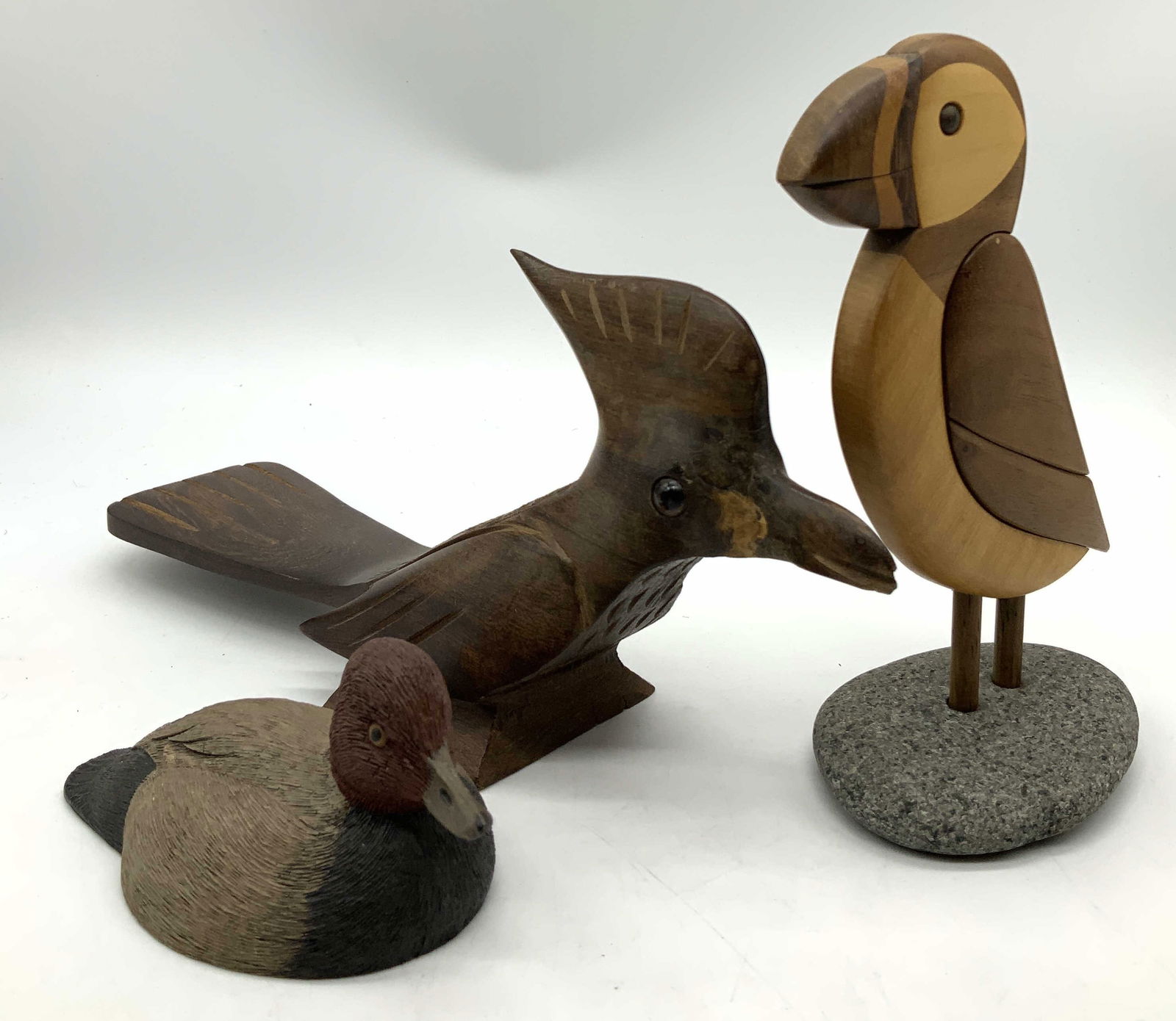 3 Carved Wood Bird Figural AmericanFowlSeries1985+: Lot includes 3 wooden bird figurines, featuring a wooden bird on a stone, a roadrunner bird & a redhead drake duck. One duck on underside reads, AMERICAN WILD FOWL SERIES 1985. Surface wear consistent