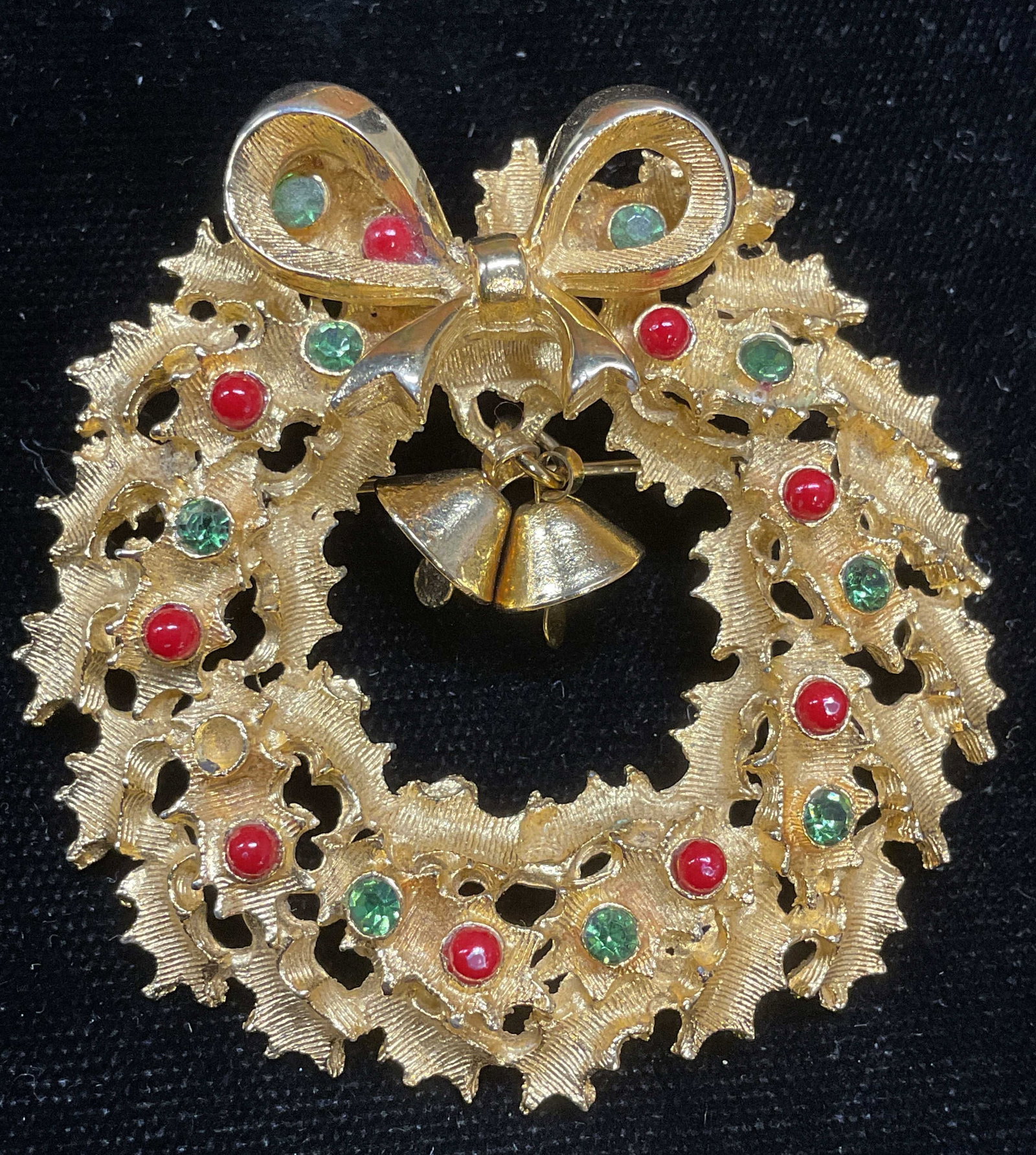 Vtg Gold Tn Crystal Holiday Wreath Brooch: Vintage gold tone green crystal red enamel Holly wreath with bells holiday brooch. Measures approx 2 inches wide. One crystal needs replacement. Some wear including scratching. Jewelry, estate jewelry
