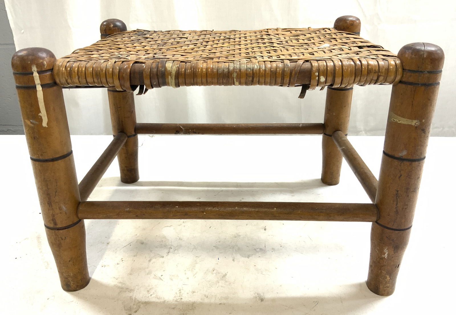 Vintage Caned & Wooden Footstool: Footstool is tan toned and wooden. Piece is vintage. Footstool has 4 wooden legs with stretchers in between & caned top surface. Footstool measures approximately 12.5 inches ling 9 inches tall 9.5 inc