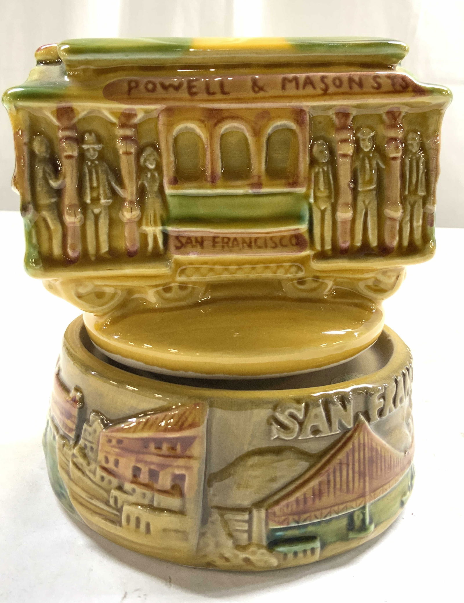 SNCO POWELL & Mason St Trolley Majolica Music Bx: Tag reads SNCO, Trolley reads POWELL & MASON ST 514 HYDE AND BEACH. Base reads SAN FRANCISCO. Majolica style ceramic music box. Piece has yellow, green & tan tones. Music box measures approximately 4.