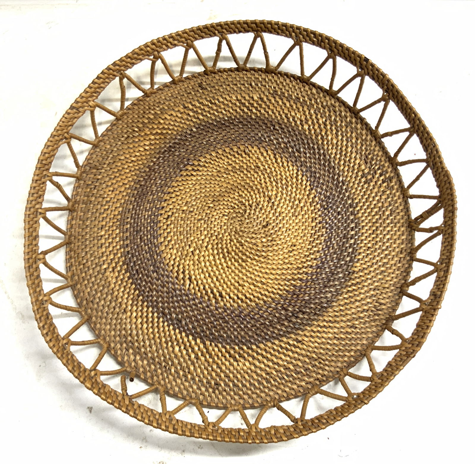 Woven Rattan Tray W Gallery Tan 16in: Tray is tan toned. Piece is woven rattan. Edges of rattan tray have gallery. Piece has brown toned ring detail. Tray has circular form. Piece measures approximately 16 inches diameter 2.25 inches tall
