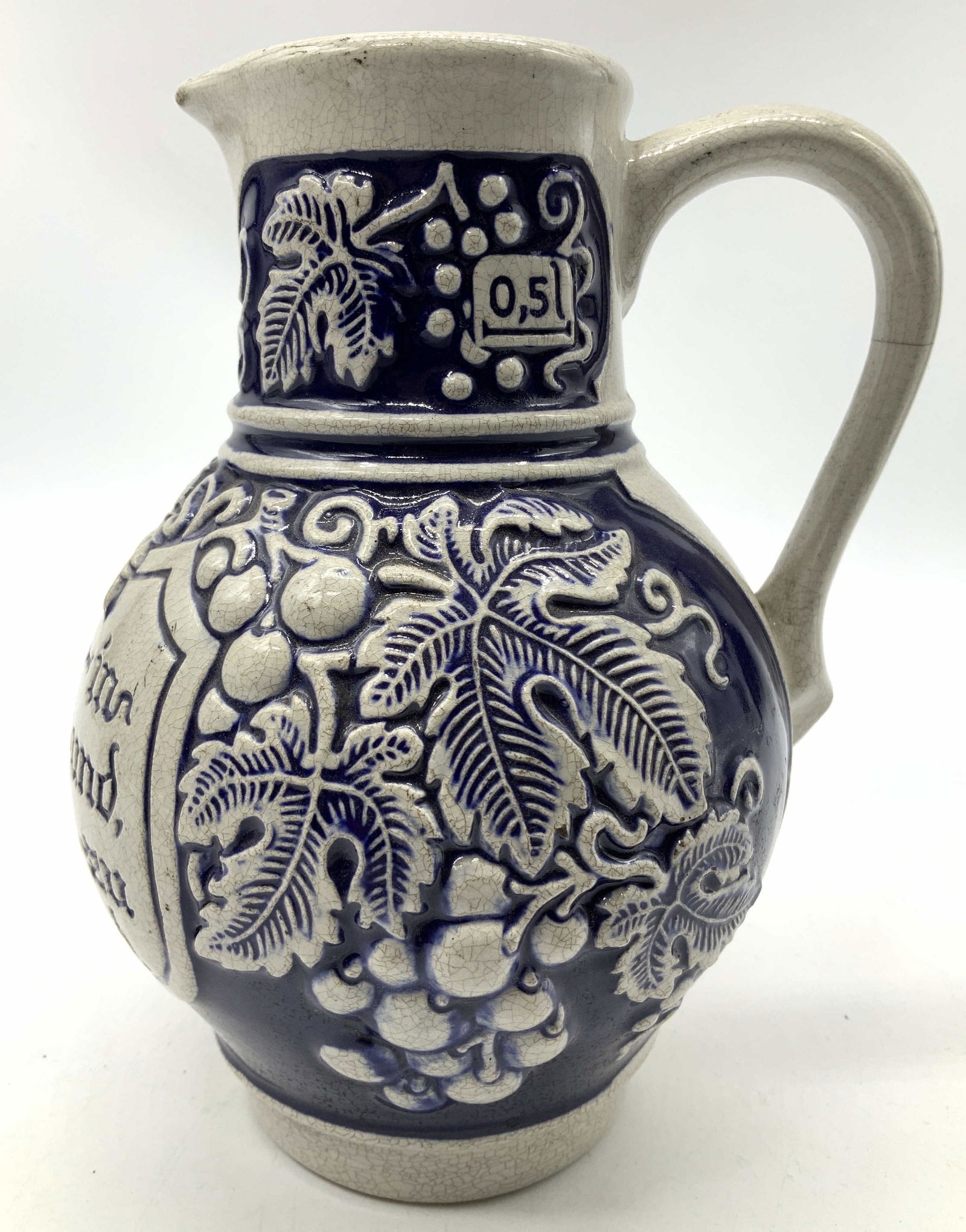 Vntg German Cobalt Blue Stoneware Grape Pitcher: Vntg German Cobalt Blue Stoneware Grape Pitcher Pitcher features a distinctive blue & gray color with intricate grape & vine details. Pitcher has German wording & appears to be stoneware material. Und