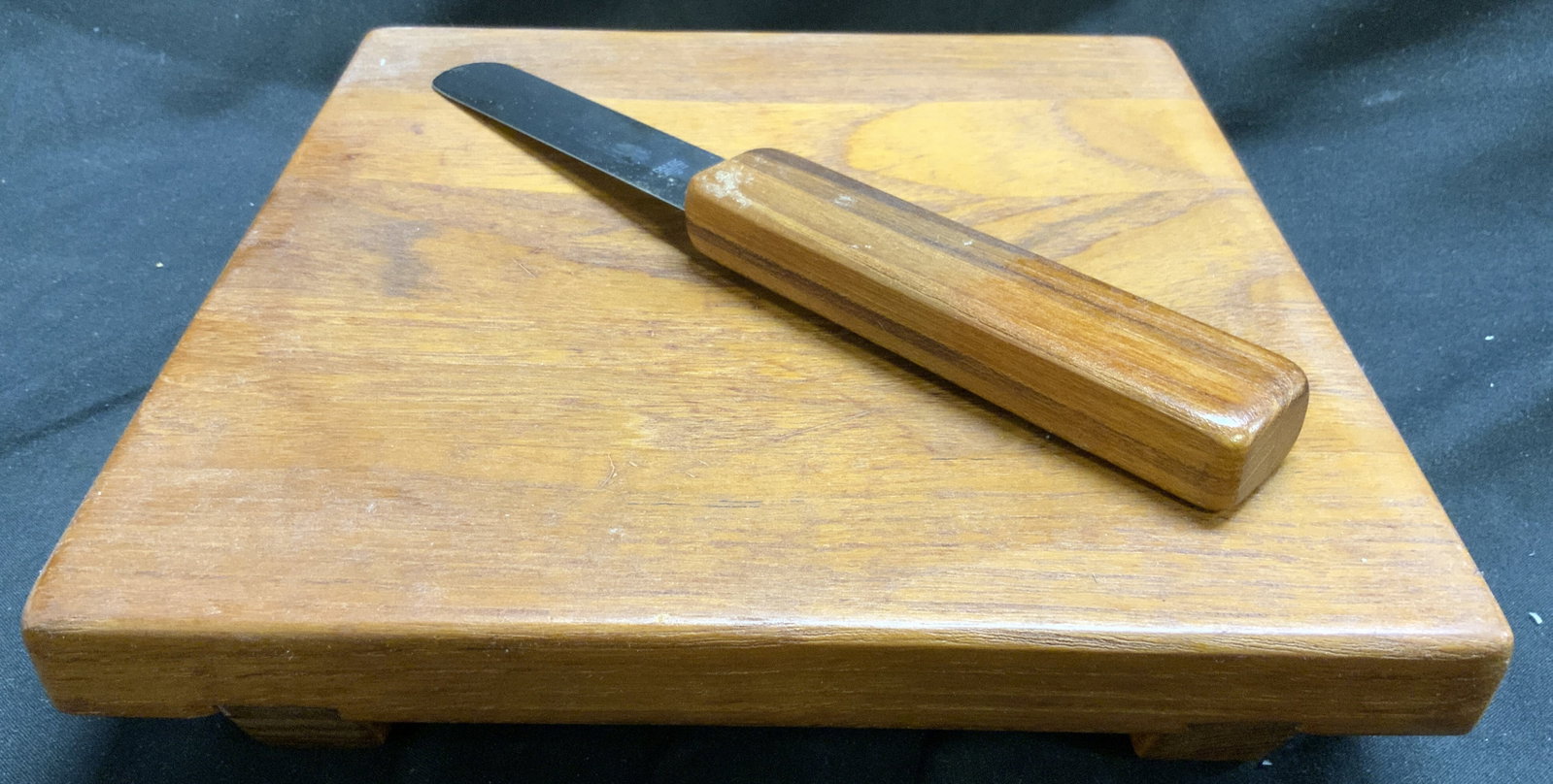 Vntg DANSK INTL Teakwood Cheeseboard & Knife: Vintage Circa 1970s. Possibly designed by Quistgaard. Underside is inscribed dansk international designs ltd ihq/thailand. Cheeseboard is tan toned and wooden. Piece has knife slot on underside and sl