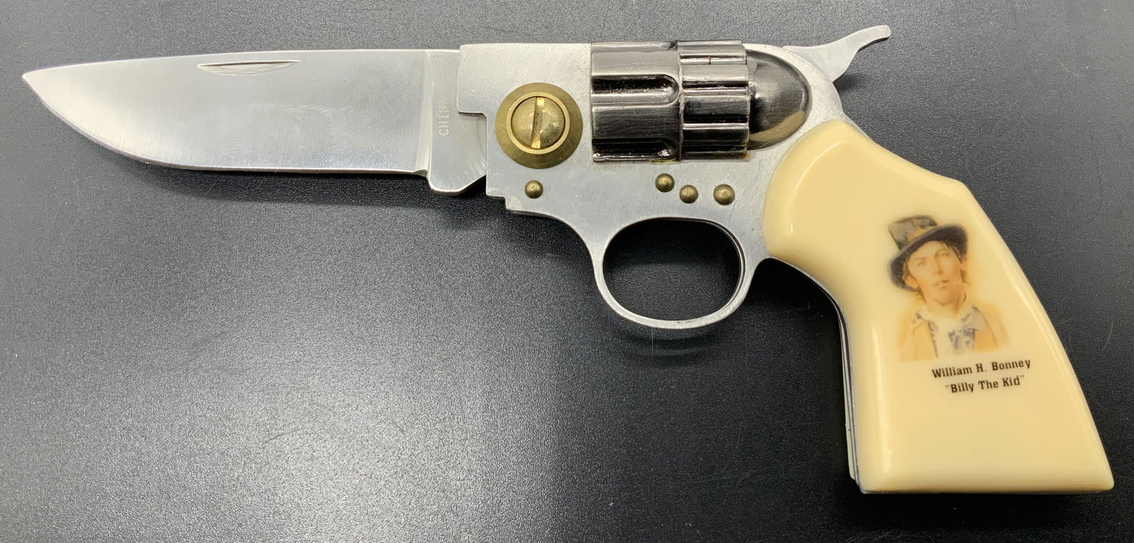 Billy the Kid Revolver Stainless Folding Knife BOX: Billy the Kid Revolver Stainless Folding Knife BOX Stainless steel knife resembling a small revolver. Revolver handle features an image of Billy the Kid. Knife comes with original box. Visible signatu