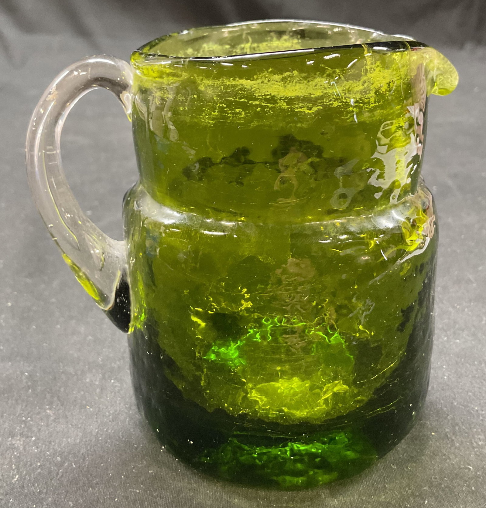 Vtg Green Glass Mini Creamer Pitcher, 4 in. Tall: Vintage green glass mini creamer pitcher. Solid green color body with clear glass handle design. Measures 4 x 4.25 inches including handle. Some surface wear including residue present on rim. Green cr