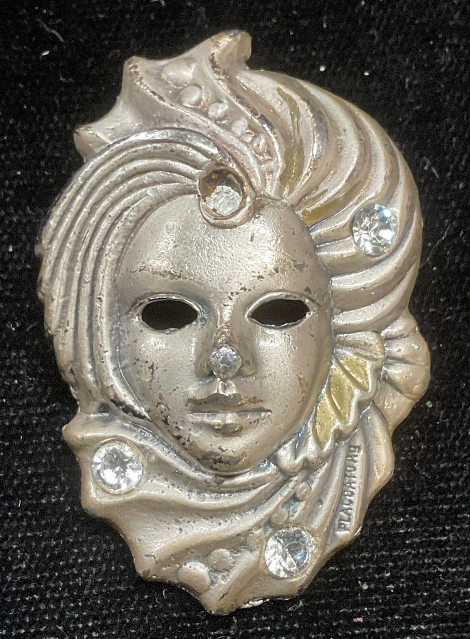 Placcato Silver Tone Crystal Mask Head Brooch: Vintage Placcato AG silver tone and colorless crystal mask motif head motif brooch. Signed. Measures approx 1.75 x 1 inches. One crystal needs replacement. Some wear including scratching. Jewelry, est