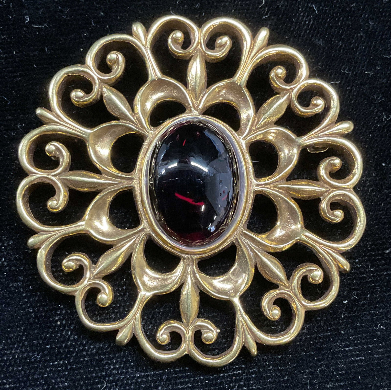 MMA BMA Gold Tn Garnet Pendant Brooch: Vintage Metropolitan Museum of Art gold tone filigree scroll pendant brooch with garnet cabochon. Signed MMA BMA. Measures approx 2 inches wide. Some wear including scratching observed. Pin needs repa