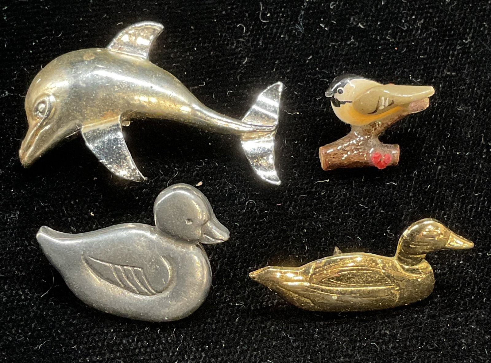 Lot 4 Gerrys Dolphin Brooch, DP Duck Pin +: Lot of 4 jewelry pieces. Signed Gerrys silver tone dolphin brooch, signed DP Ltd silver tone duck pin, gold tone duck pin, and hand painted bird pin. Largest approx 1.25 x .75 inches. Some wear includ