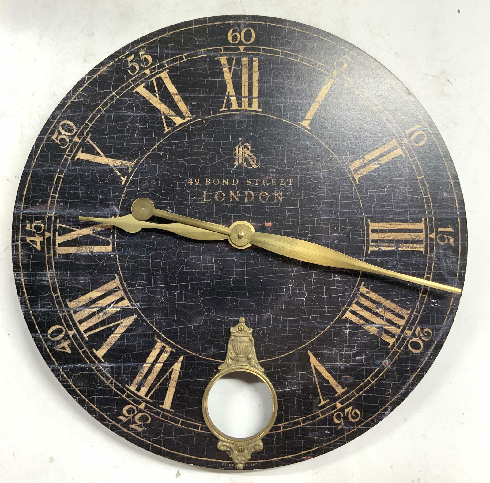 49 Bond Street LONDON Clock Face 18in: Clock face reads 49 BOND STREE LONDON. Clock face is black and tan toned with gold toned metal hands and tan toned Roman numerals. Clock face has circular form. Crafted from board. Tag on backside rea