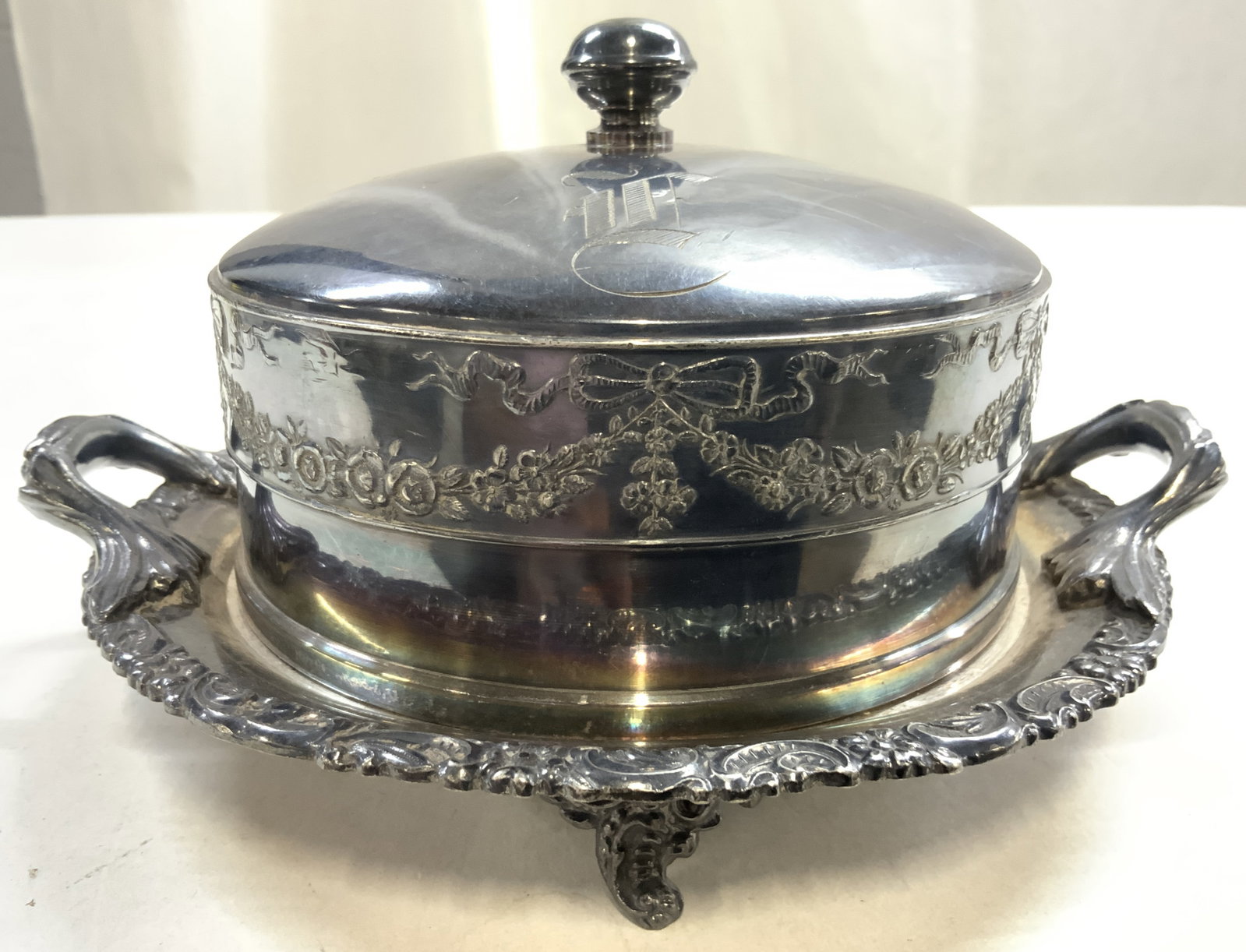 MERIDEN B CO Quad Plated Mngrmd Footed Butter Dish: Underside is inscribed MERIDEN B CO QUADRUPLE PLATES. Butter dish is vintage. Piece is quadruple plated. Dish has 4 scrolled feet. Piece has handles at sides. Includes lid with monogram F. Butter dish