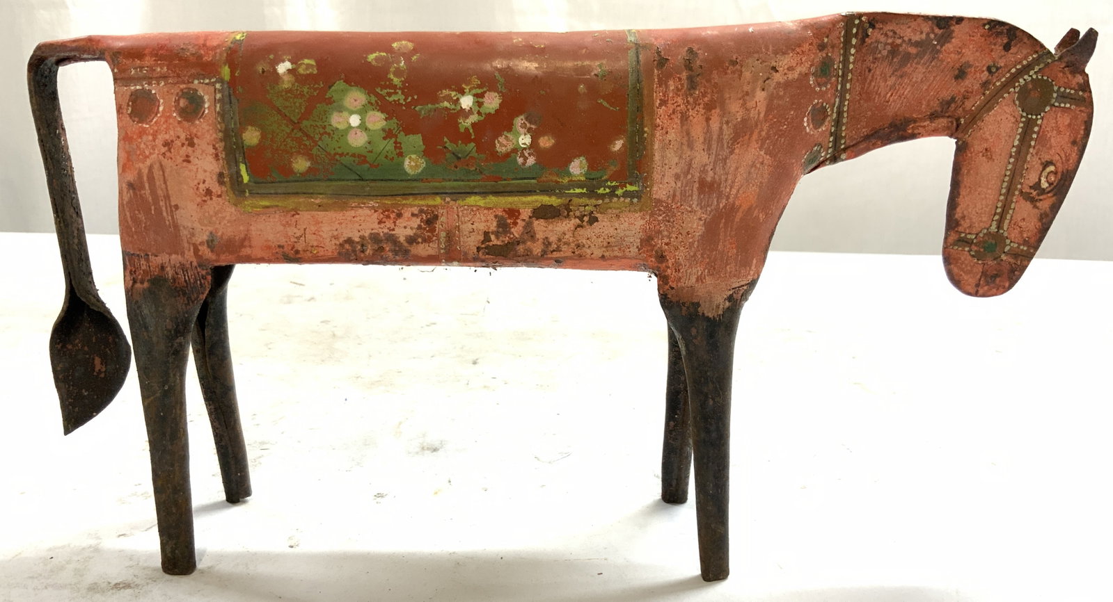 Vntg Folk Art Metal Horse Circa 1970s: Figure depicts a donkey/horse. Piece is vintage and metal. Folk art metal horse circa 1970s. Piece is salmon pink toned with floral and leaf detailed saddle. Measures approximately 11 inches long 6 in