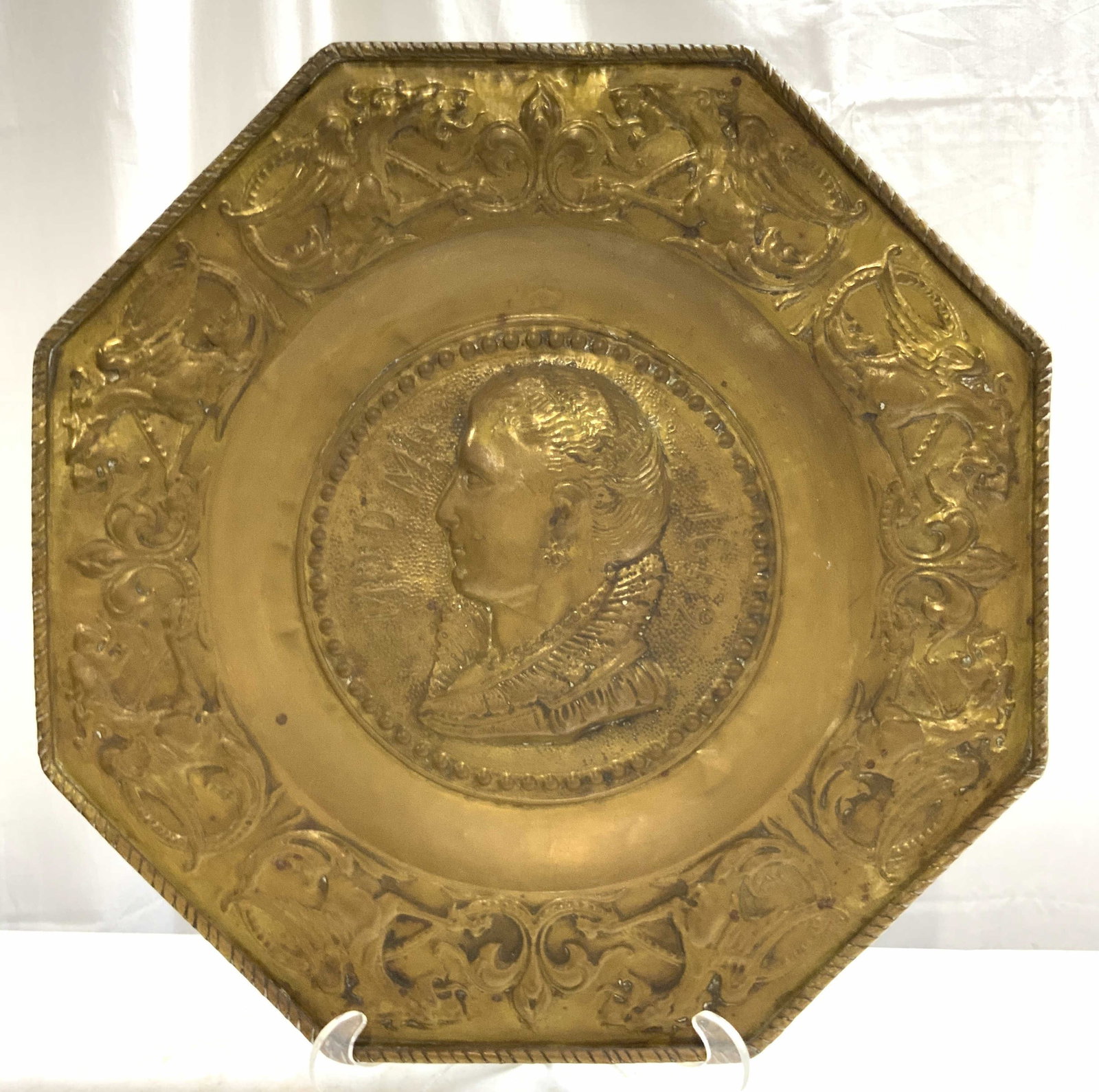 Antq XL French Gilt Metal Octagonal Charger 23 in: Charger is antique. Piece is gilt metal, possibly brass. Piece has profile portrait image of female figure. Border has dragon and scroll pattern detail. Charger has octagonal form. Piece has lipped ri