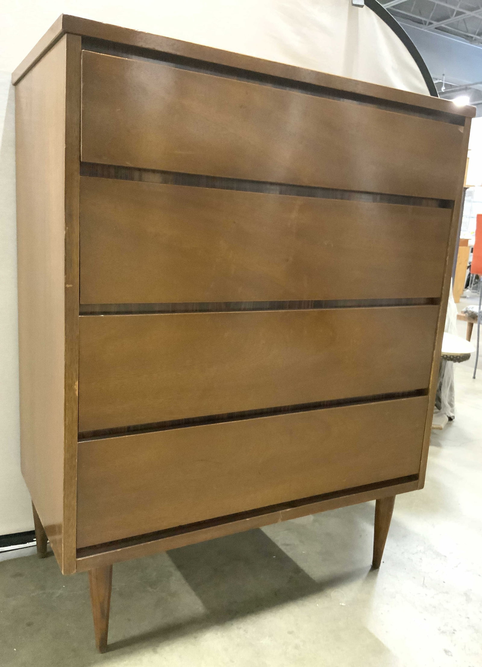 BASSET MCM 4 Drawer Tapered Leg Tallboy Dresser: Trademark inside top drawer reads BASSET FURNITURE INDUSTRIES. Dresser is tan toned and wooden. Piece has 4 drawers, each with dovetailing. Dresser is light brown toned. Possibly wooden possibly venee