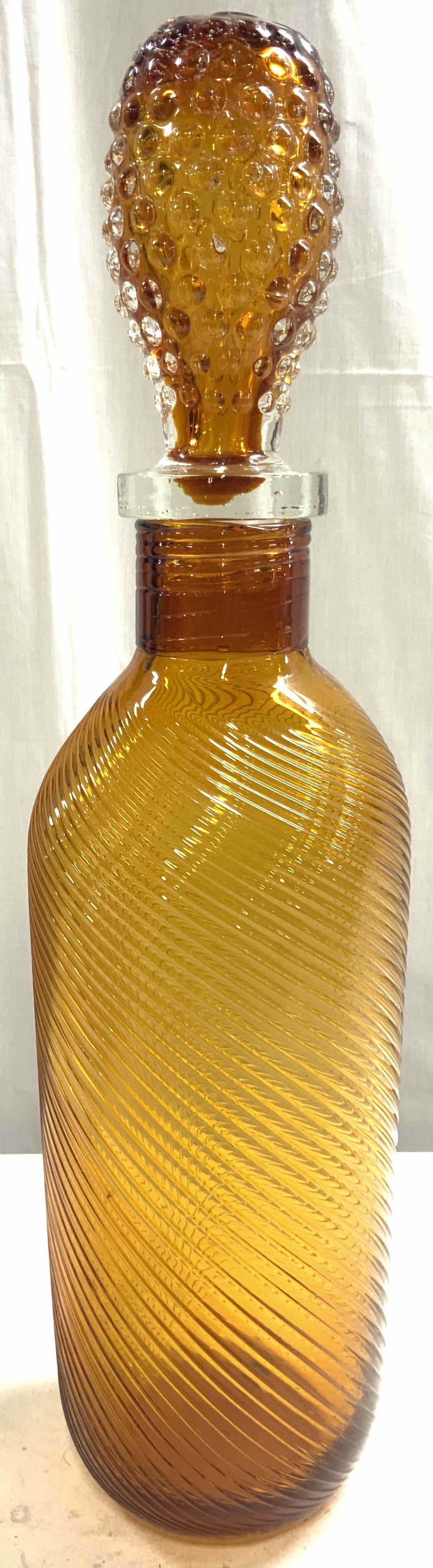 EMPOLI Style Art Glass Swirl Decanter&Stopper 19in: Decanter is orange toned and glass. Piece is EMPOLI style. Decanter has swirl style exterior. Piece has stopper with studded/beaded detail. Decanter is Possibly hand blown due to pontil on underside. 