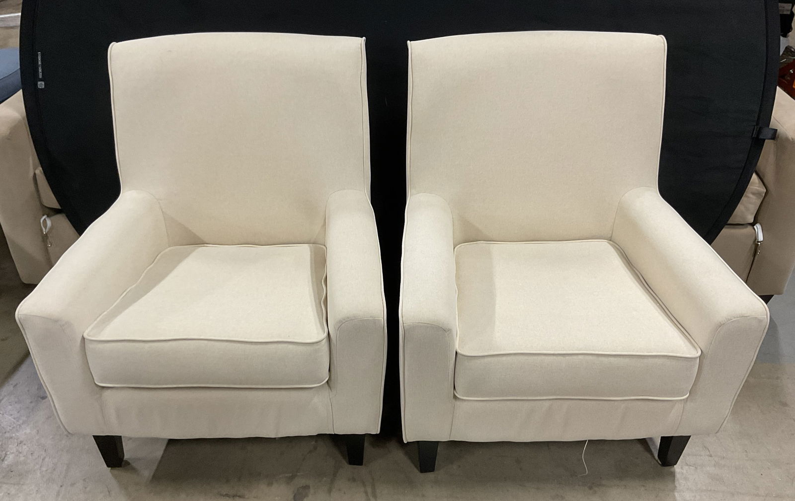 Pair Cream Upholstered Armchairs: Pair of armchairs. Cream upholstered material, feels like cotton. Contemporary design. Wood feet. Measure approx 28.5 inches wide, 18 inches deep, 34.5 inches tall. Minimal surface wear observed. Armc