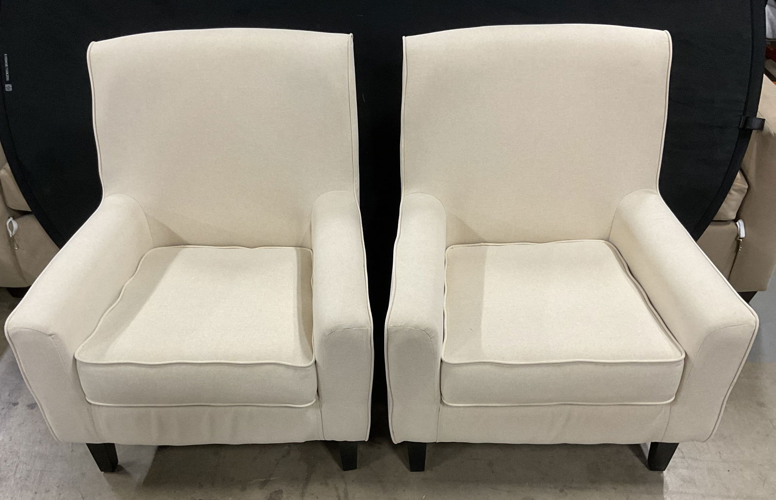Pair Cream Upholstered Armchairs: Pair of armchairs. Cream upholstered material, feels like cotton. Contemporary design. Wood feet. Measure approx 28.5 inches wide, 18 inches deep, 34.5 inches tall. Minimal surface wear observed. Armc