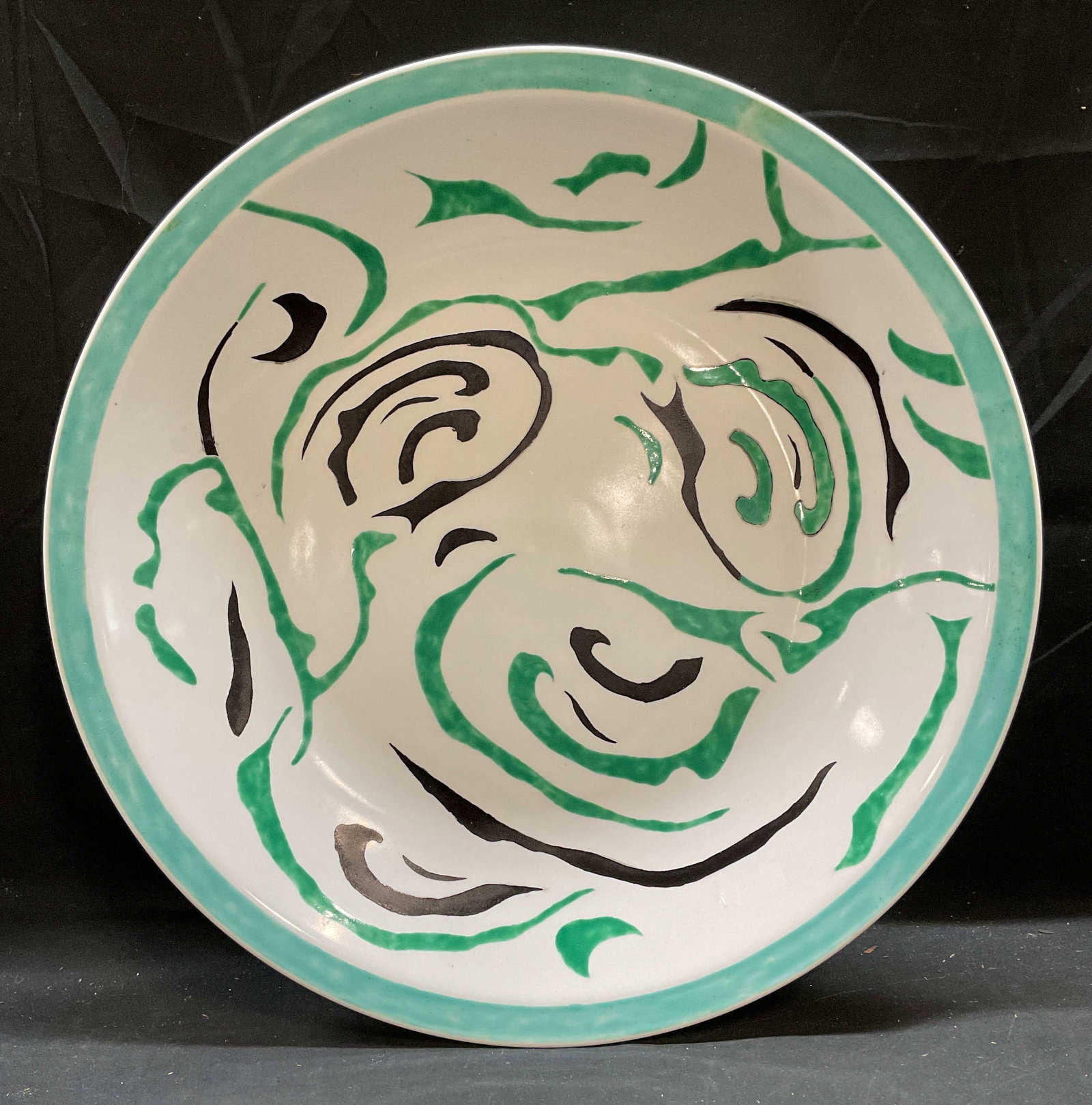 Signed Green Black Porcelain Centerpiece Bowl: Signed porcelain centerpiece bowl. Hand painted green and black on white with abstract pattern. Signed on underside, illegible. Possibly Bianco. Measures approx 20 inches wide. Piece has weight. Some 