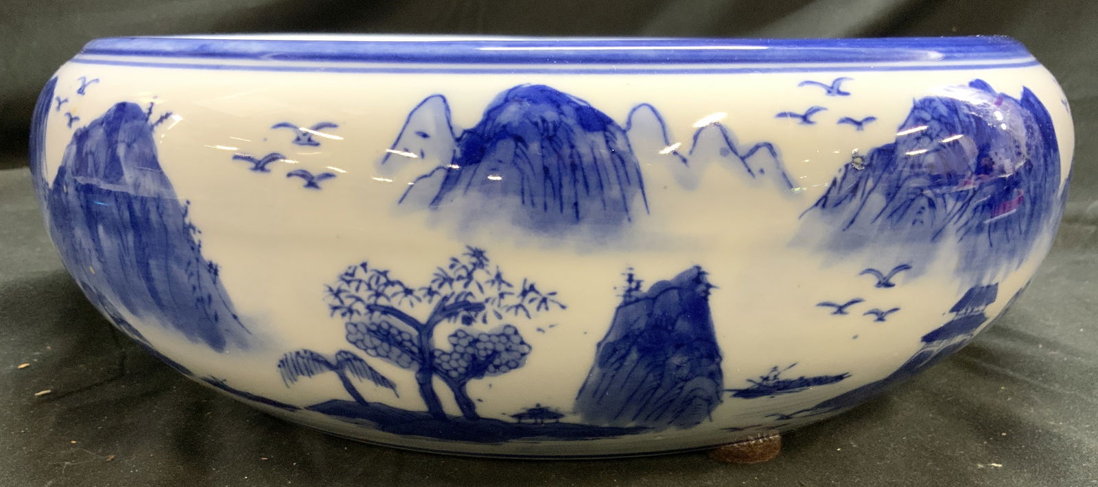 Vintage Asian Porcelain Bowl Vessel W Landscape: Bowl is vintage. Asian porcelain vessel. White with blue toned hand painted landscape detail with birds and mountains. Piece has blue toned painted rim. Vessel measures approximately 12 inches diamete