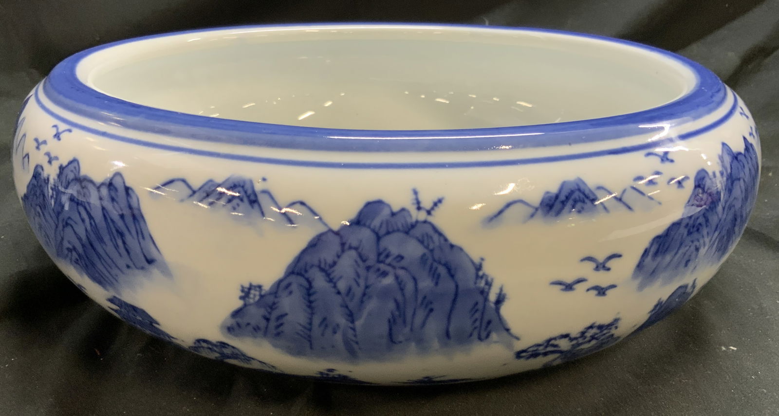 Vintage Asian Porcelain Bowl Vessel W Landscape: Bowl is vintage. Asian porcelain vessel. White with blue toned hand painted landscape detail with birds and mountains. Piece has blue toned painted rim. Vessel measures approximately 12 inches diamete
