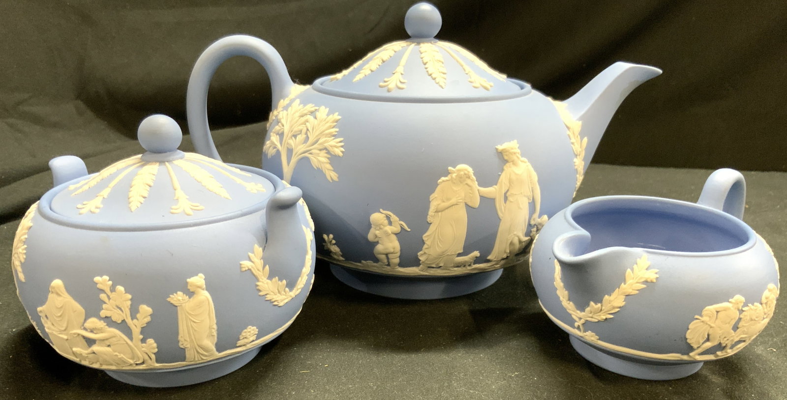 WEDGWOOD Set 3 Vintage Teapot Creamer & Sugar Engl: Undersides are inscribed WEDGWOOD MADE IN ENGLAND 1955. Lot includes 1 creamer dish, 1 sugar dish with lid & 1 teapot with lid. Each piece is light blue with white toned figural, leaf & tree detailing