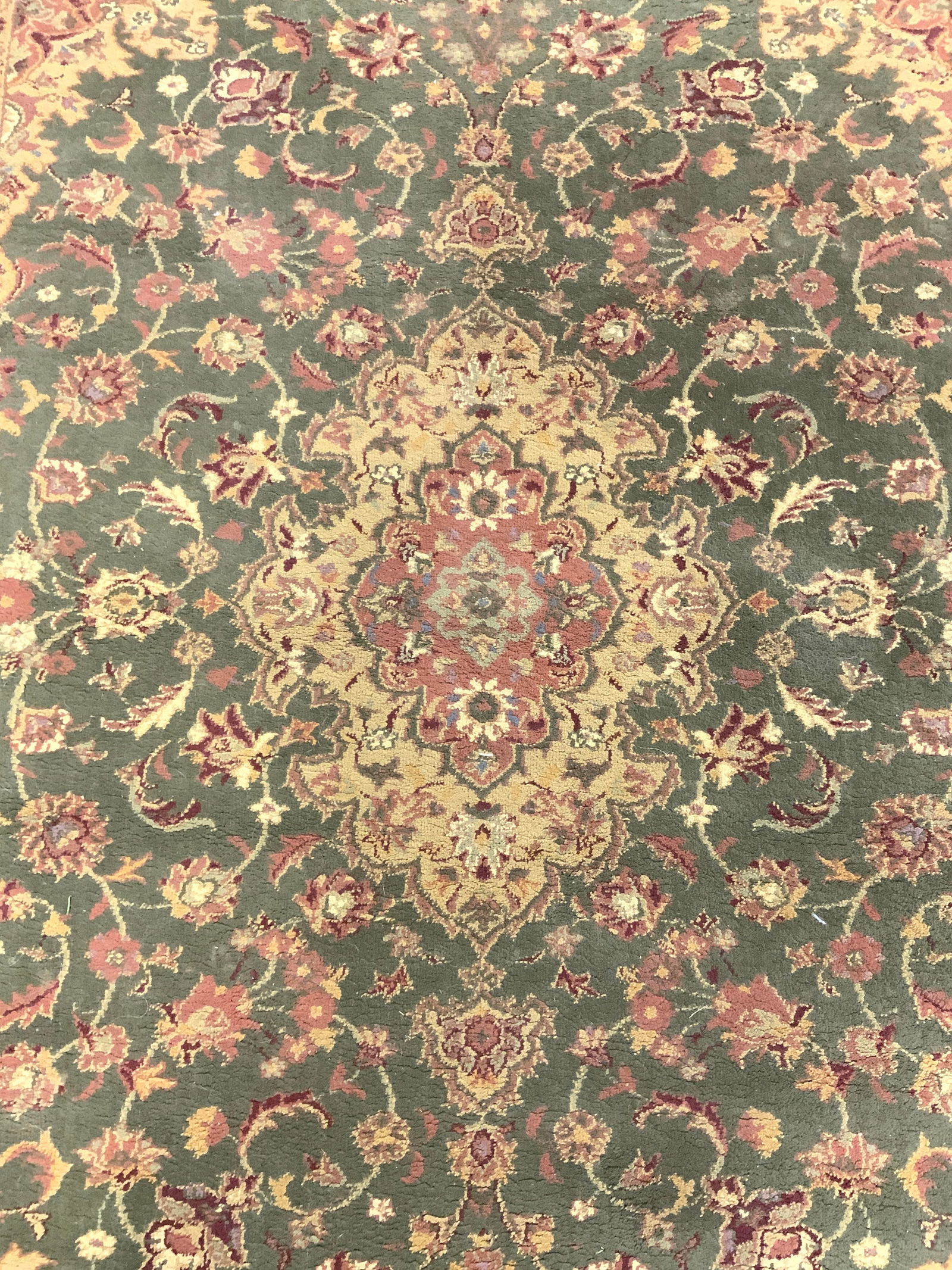 Oriental Weavers Of America Frngd Wool Area Rug: Tag on underside reads OREINTAL WEAVERS OF AMERICA. Rug is wool. Piece is olive toned with intricate multi toned floral motif detail. Rug has tan toned fringes at edges. Rug measures approximately 91