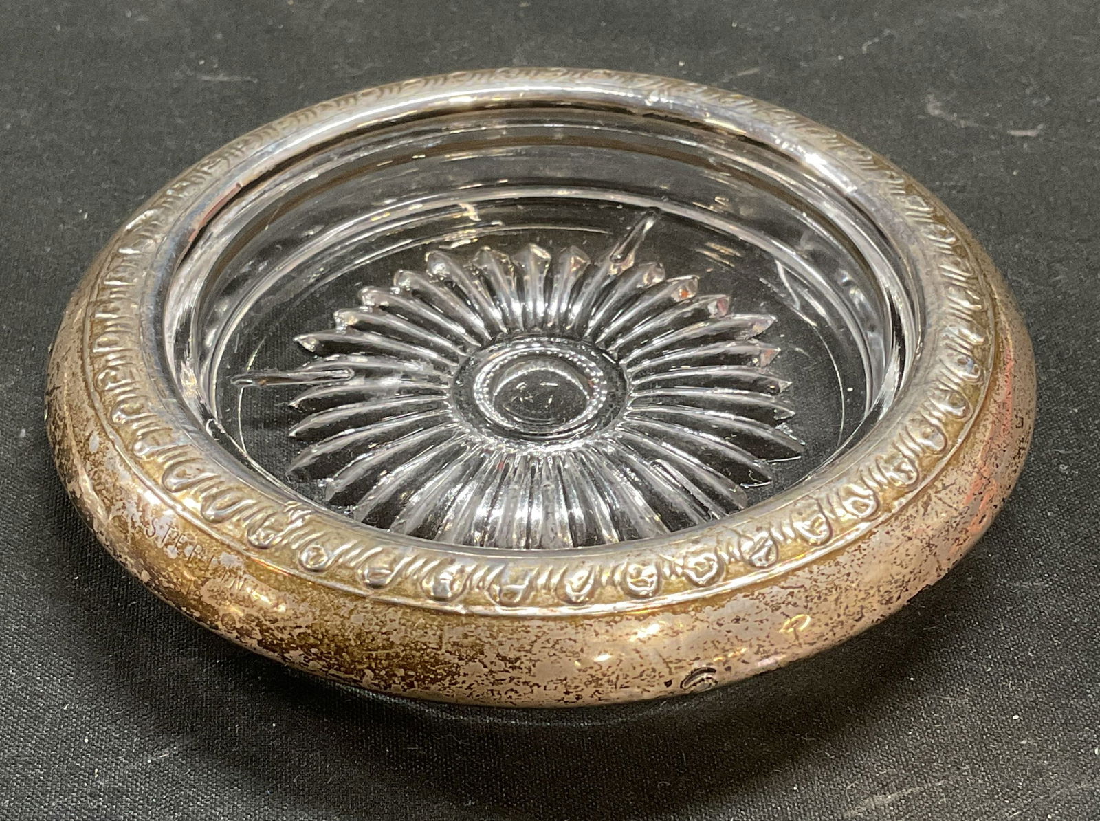 Vintage Sterling Silver Rim & Glass Coaster: Vintage sterling silver rimmed glass coaster. Raised scroll motif. Marked sterling. Thick walled glass. Measures approx 4 inches wide. Wear including patina, warping, scratching observed. Sterling sil