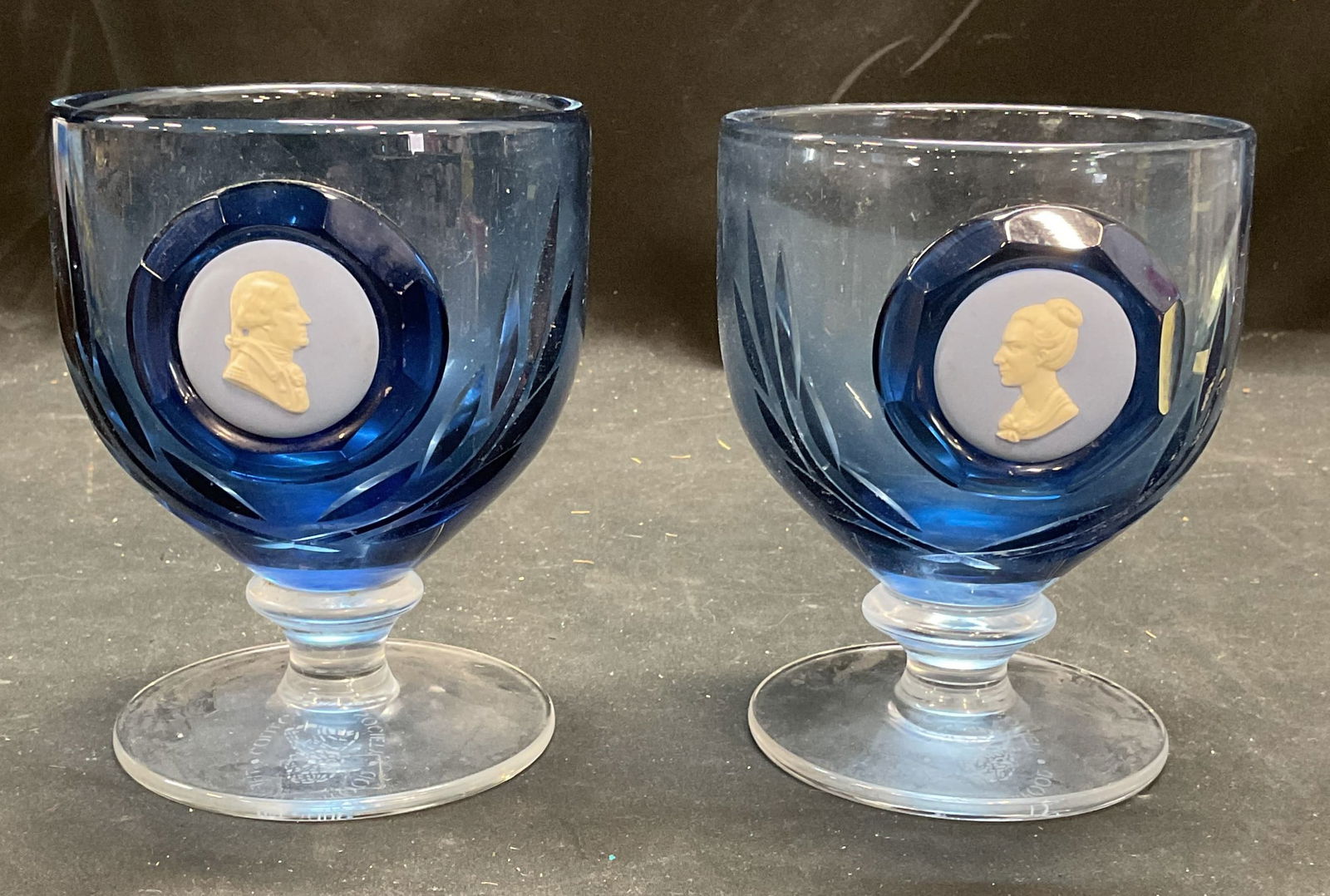 Pair Wedgwood Glass & Jasper Cameo Goblets England: Pair of Wedgwood blue to clear cut glass cameo goblets with blue and white Jasperware cameos. Signed Wedgwood Collectors Society. Made in England. Measure approx 4 x 5.25 inches each. Some scratches.