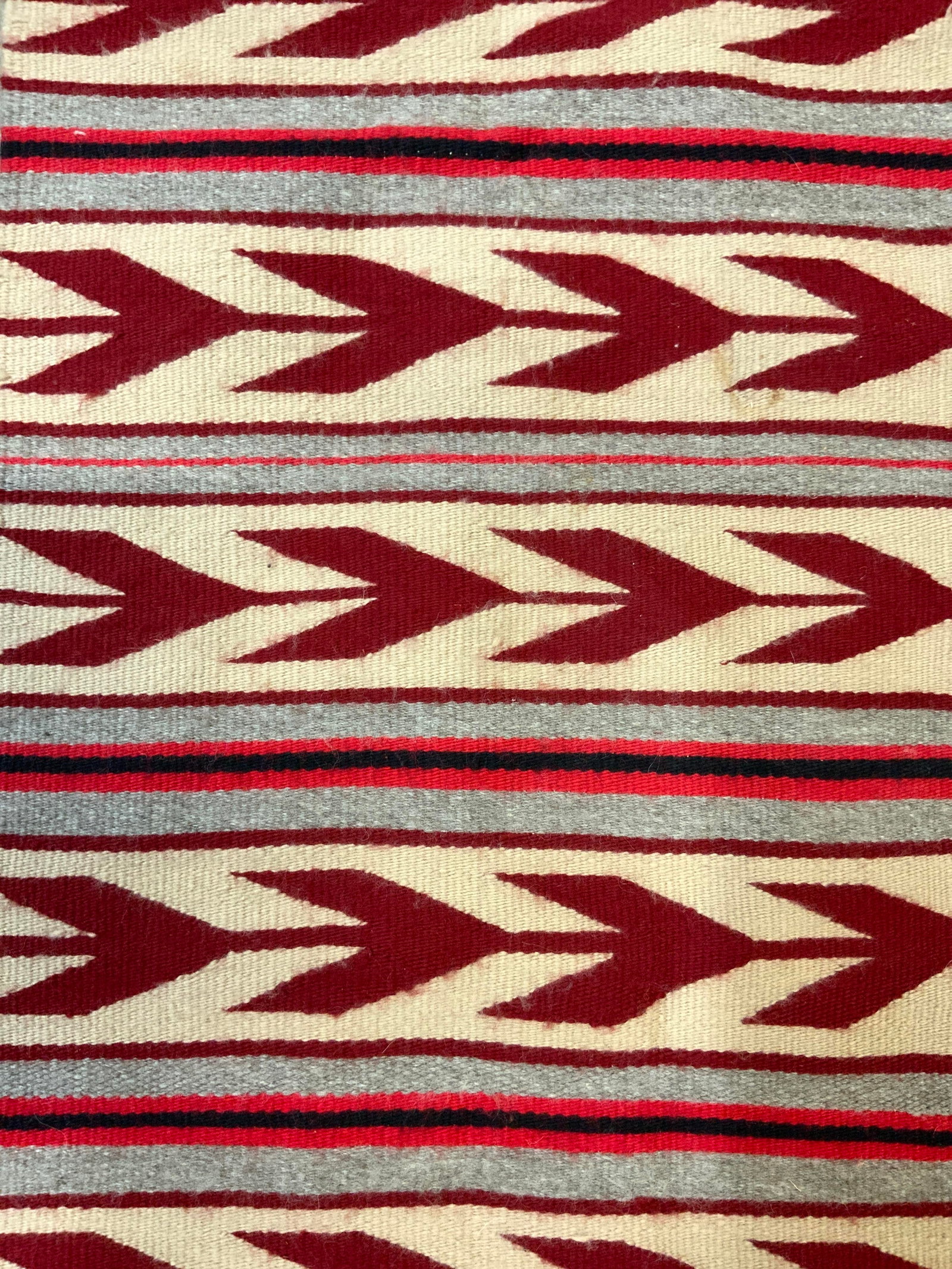 Vintage Tribal Style Handmade Wool Rug: Rug is handmade and wool. Piece has multi toned geometric tribal style detail. Red, black, sand and tan tones. One side has cream toned fringes. Piece measures approximately 39 inches long 19 inches w