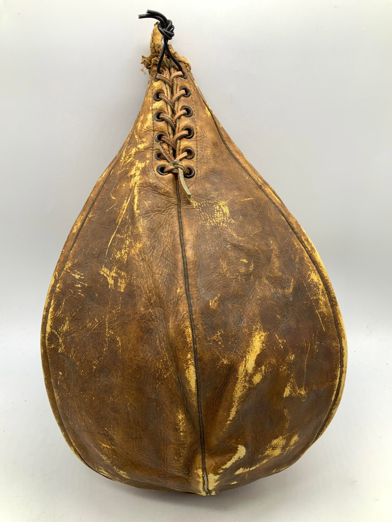 Vntg TRADEMARKED Genuine Cow Hide Punching Bag: Vntg TRADEMARKED Genuine Cow Hide Punching Bag Punching bag features a pear shape & a laced closure at the top. Visible trademark/lettering but not legible. Surface wear consistent to age, use & expos