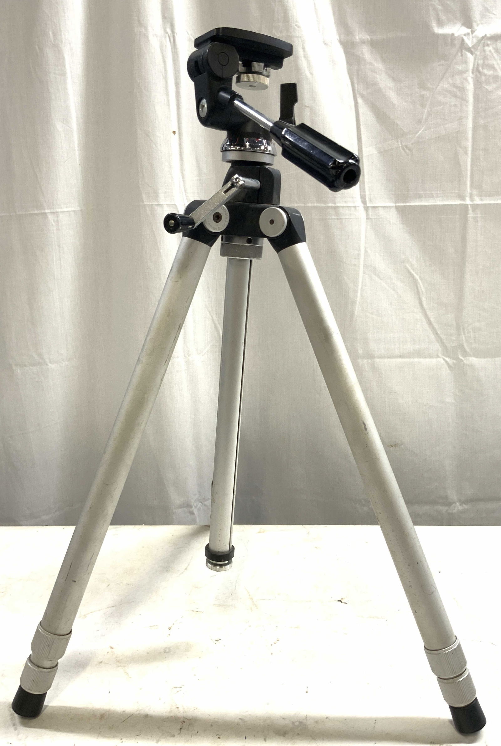 SLIK TRIPOD Metal & Plastic Adj Tripod JAPAN: Tripod is inscribed SLIK TRIPOD JAPAN. Tripod is metal and plastic. Piece has 3 adjustable legs. Top of piece has crank to adjust height and handle to adjust shooting angle. Tripod measures approximat