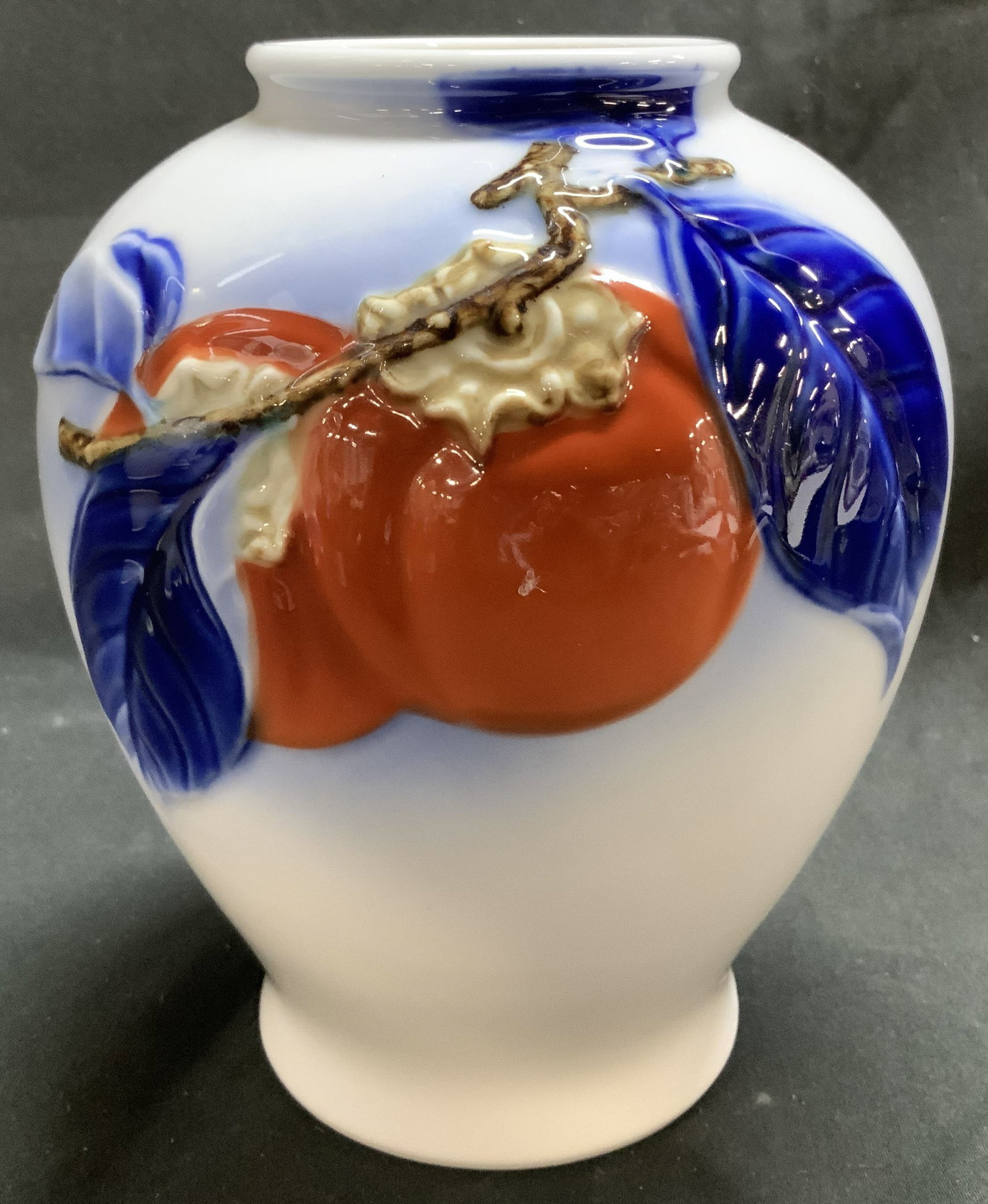 Vntg Fukagawa Arita Persimmons Motif Porc Vase: Vntg Fukagawa Arita Persimmons Motif Porc Vase Porcelain vase features hand-painted vibrant orange persimmons and blue leaves. Signed with Asian characters on underside. Surface wear consistent to age