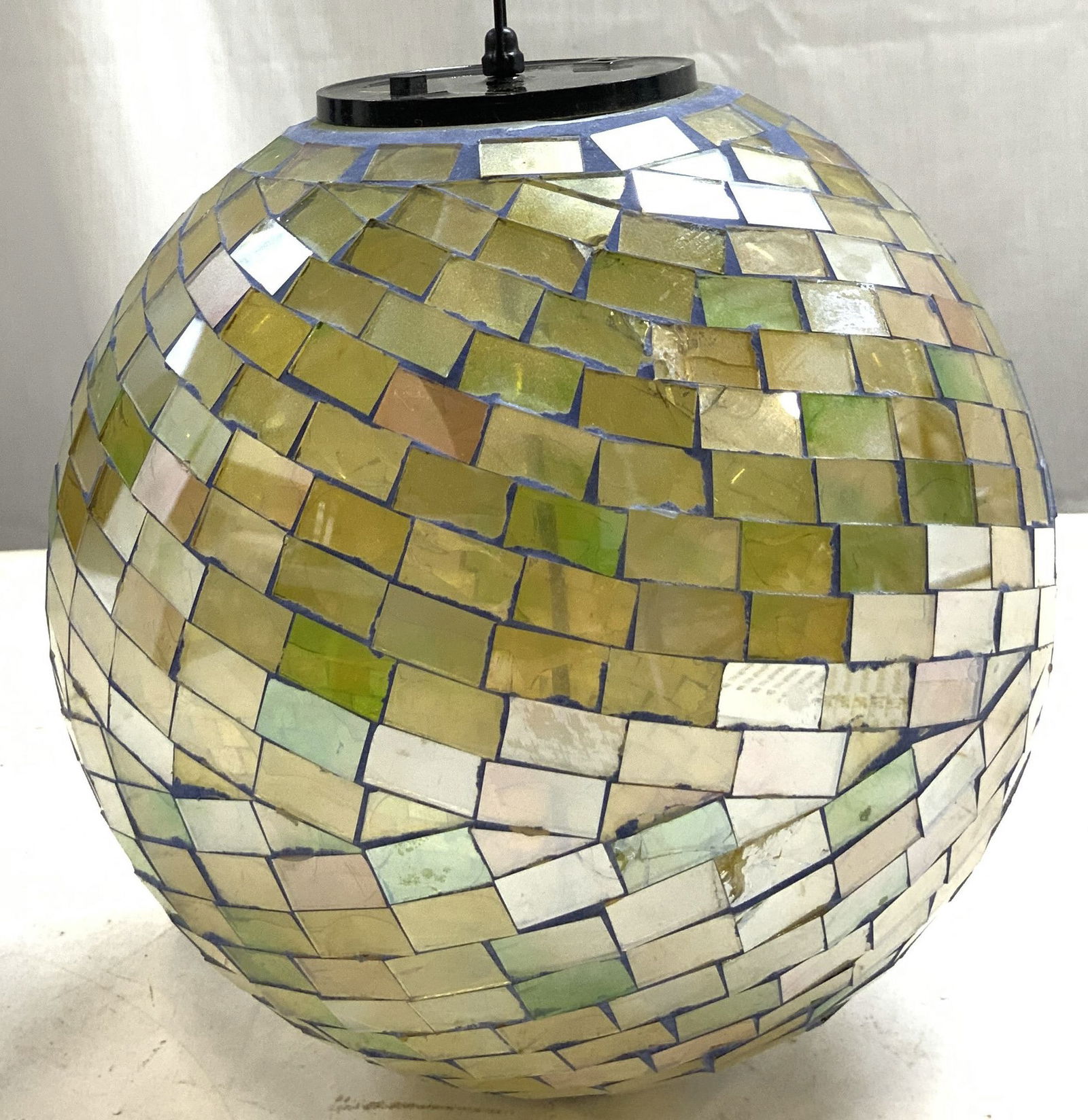 Hanging Glass Mosaic Ball Ceiling Ornament: Ornament has metal chain link with hook at top. Piece is glass mosaic with green and yellow tint to glass. Underside of piece has black toned metal area. Piece measures approximately 7.5 inches wide 2
