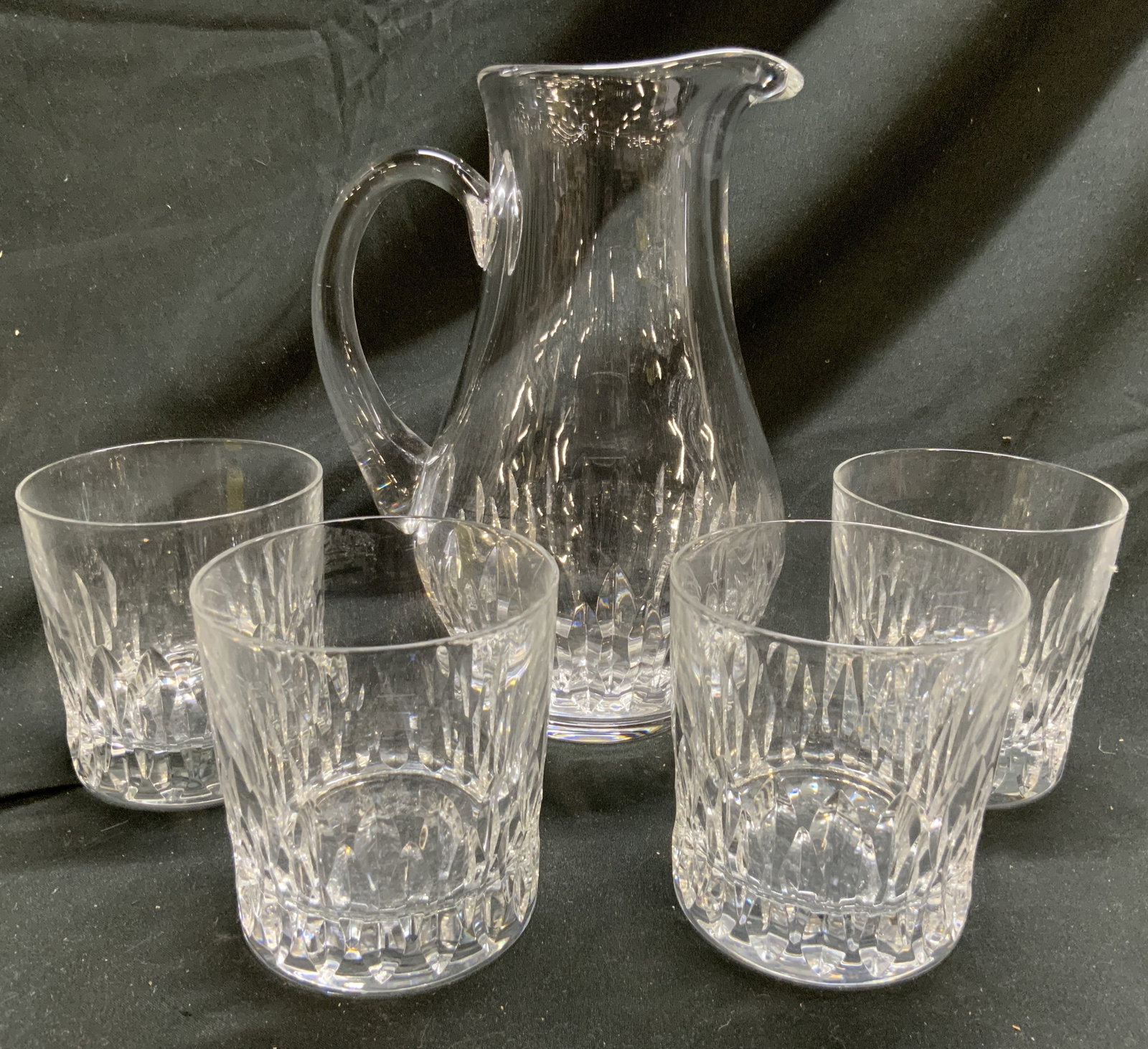 CDA Set 5 Crystal Pitcher & Lowball Cocktail Glass: Undersides of cocktail glasses are inscribed CDA Lot includes 1 pitcher and 4 cocktail glasses. Each piece in lot is crystal. Lower halves of each have relief detail. Pitcher measures approximately 8