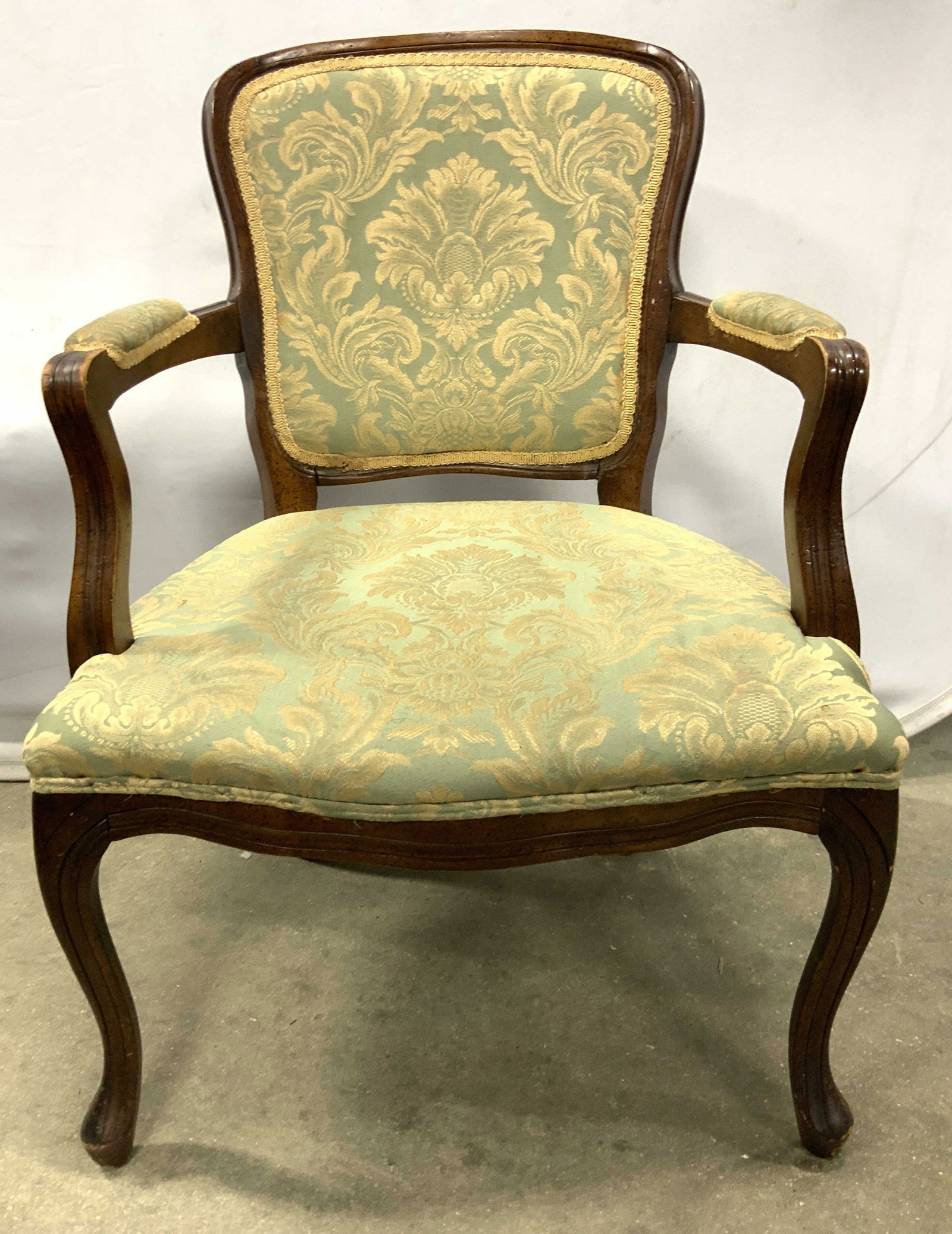 Vtg Country French Wooden Bergere End Chair: Bergere arm chair is vintage. Country French chair with brown toned carved wooden frame. Gimp and double welting to edges of upholstery. Chair is upholstered with light blue and gold toned floral and