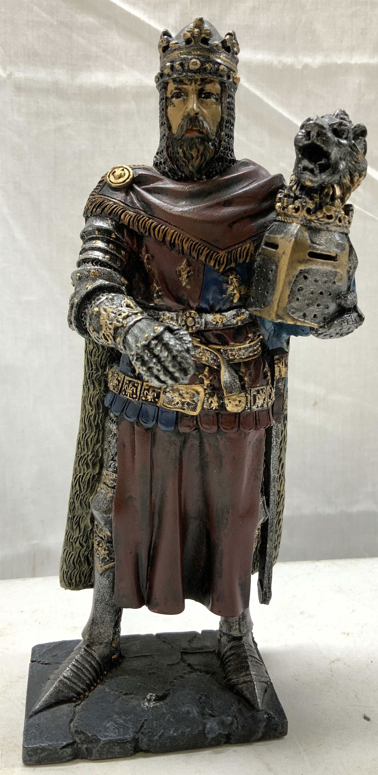 Richard Coeur de Lion Medieval Figurine: Richard Coeur de Lion Medieval Figurine Figurine depicting a medieval knight in armor, adorned with a crown and holding a lion-crested helmet. Figurine appears to be resin material. Surface wear consi